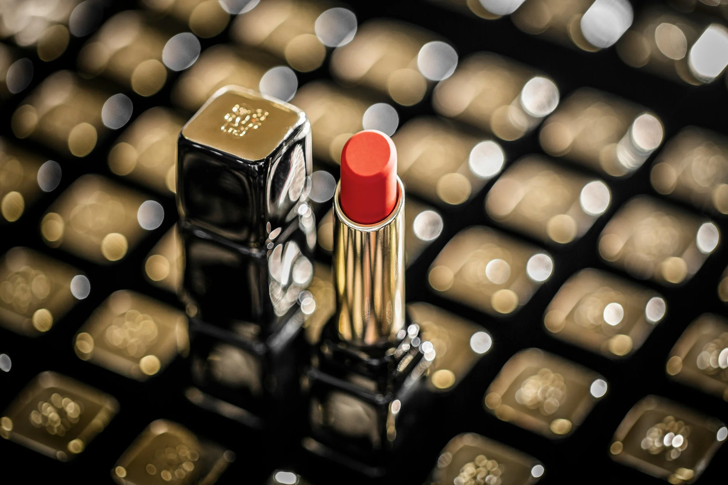 Guerlain Rouge G luxury lipstick displayed in a gold and black case surrounded by multiple Guerlain lipstick caps, highlighting the Maison’s refined beauty craftsmanship