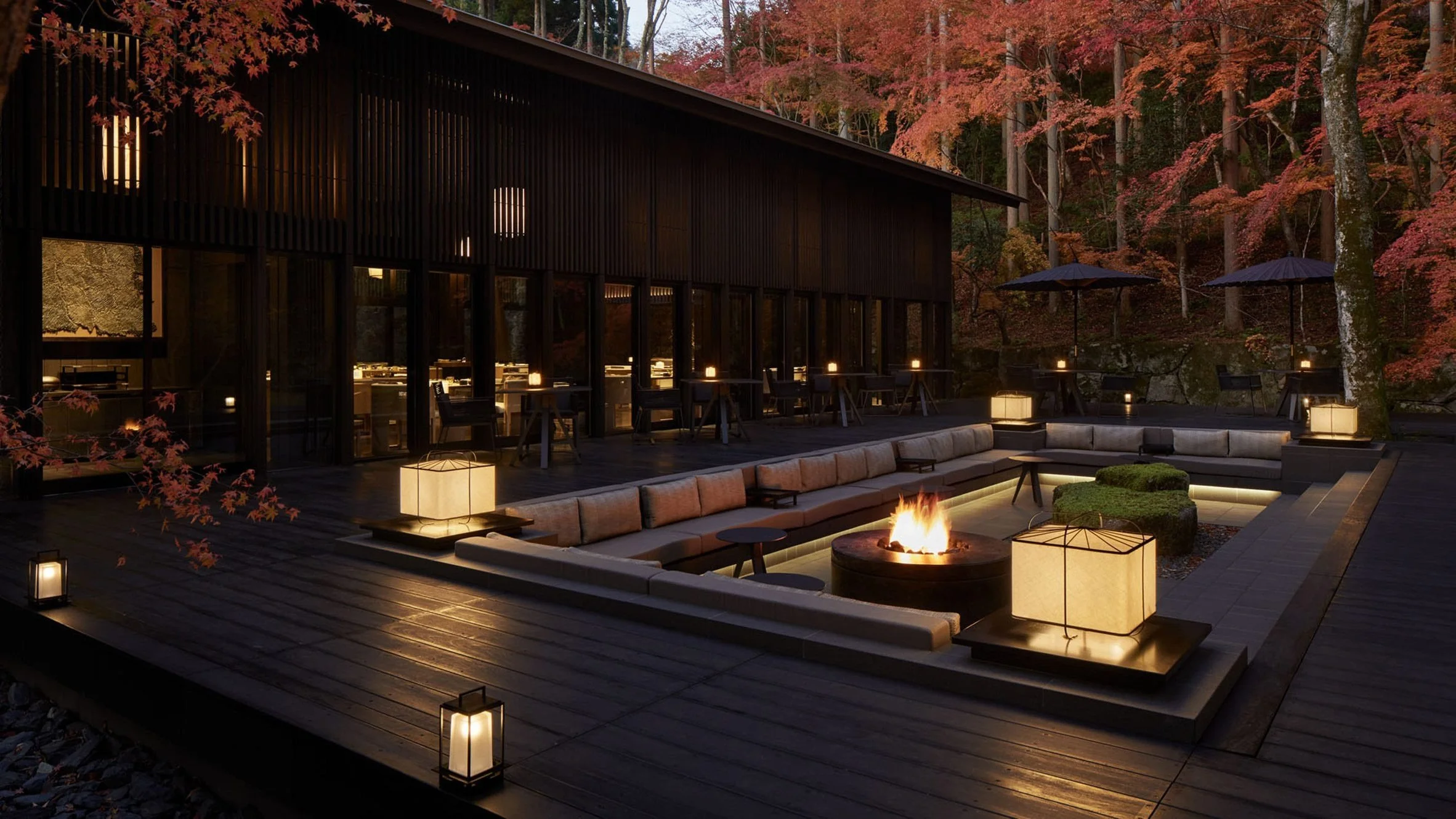 Aman Kyoto terrace in Japan with autumn maple trees, warm lanterns, outdoor seating, and a central fire pit in a forest setting.