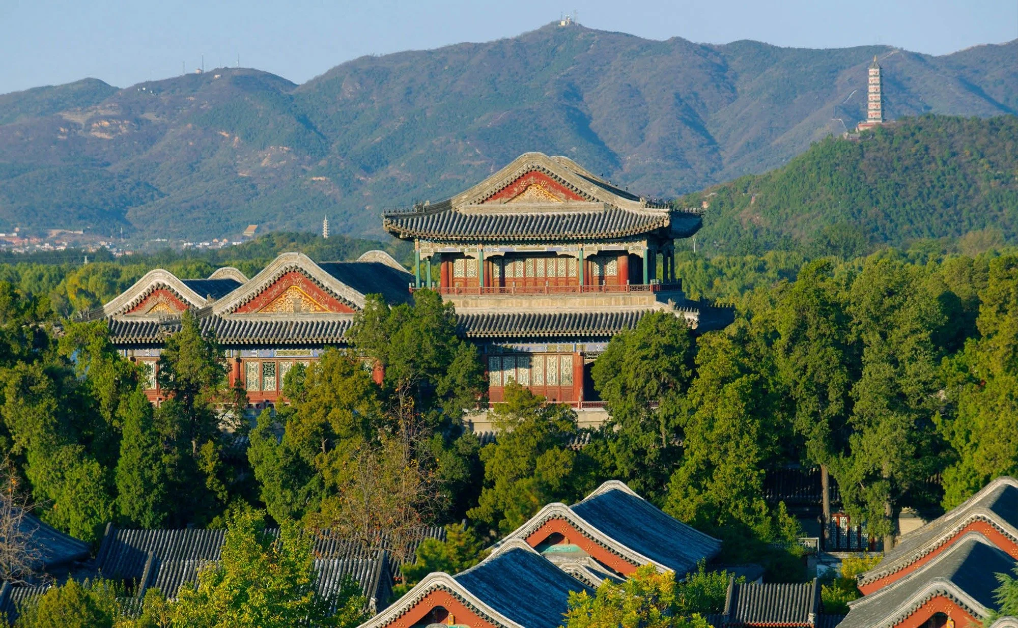 Amandayan in Lijiang, China, with traditional Chinese architecture surrounded by trees and mountain scenery.
