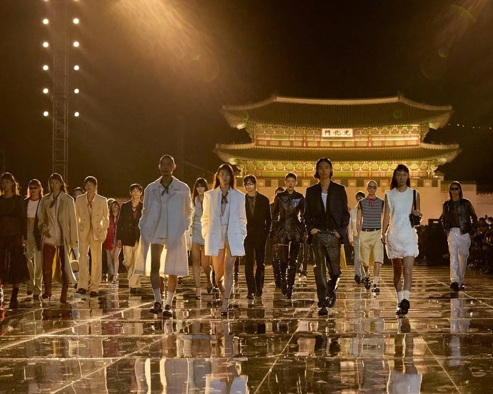 AMI Paris runway show in front of Gyeongbokgung Palace in Seoul featuring models walking across a reflective runway during the brand’s international fashion presentation