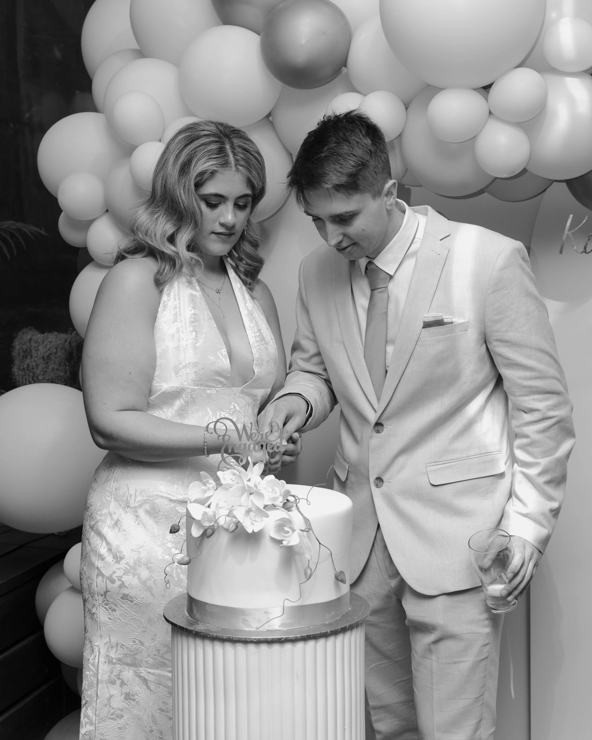 A couple dressed in formal attire cutting a wedding cake at their celebration.