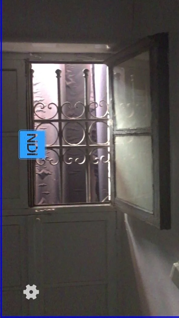 A window with decorative iron bars and partially open metal shutters, with light coming through from outside.