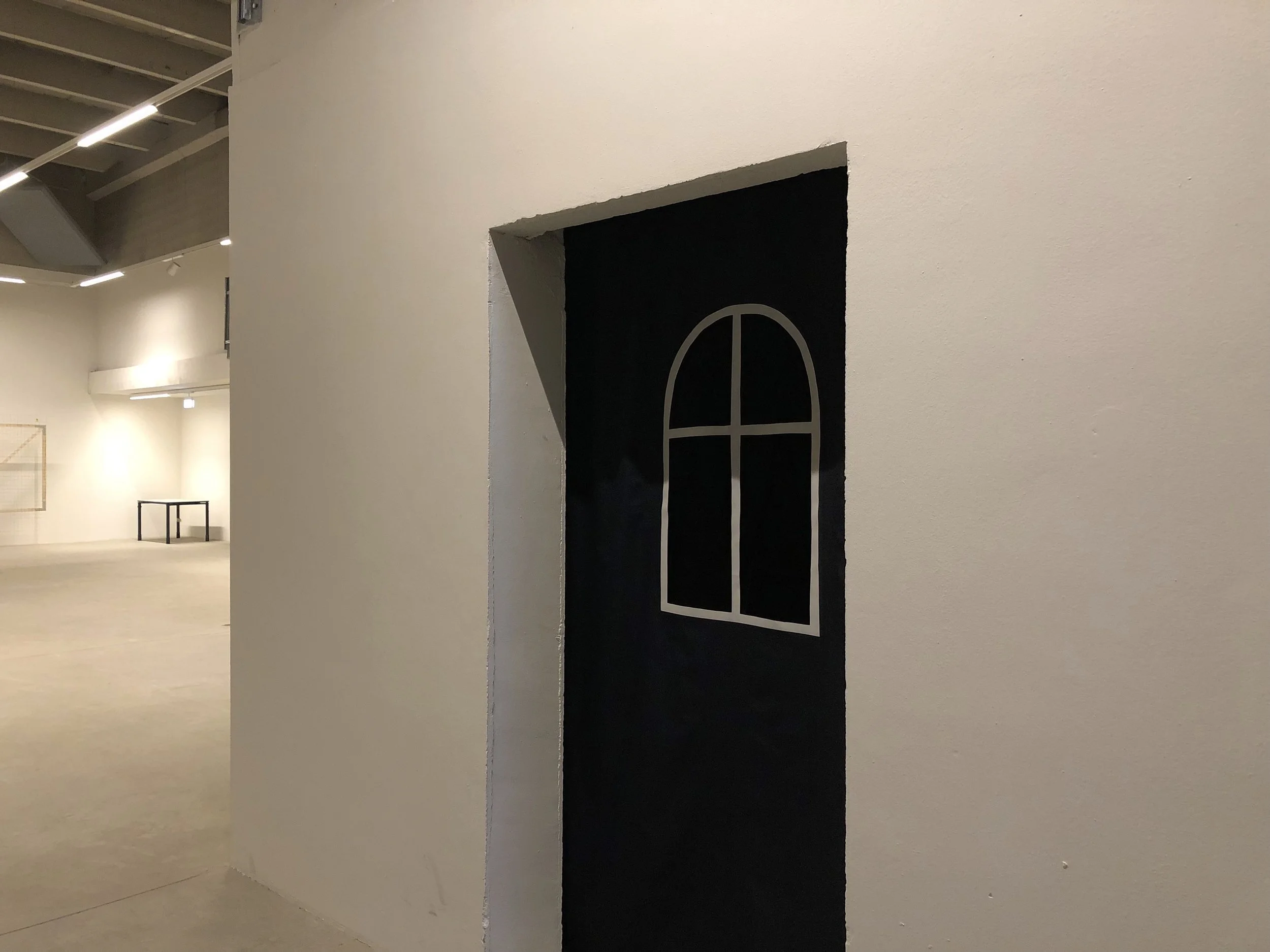 A wall with a doorway painted black, featuring a white outline of a window.