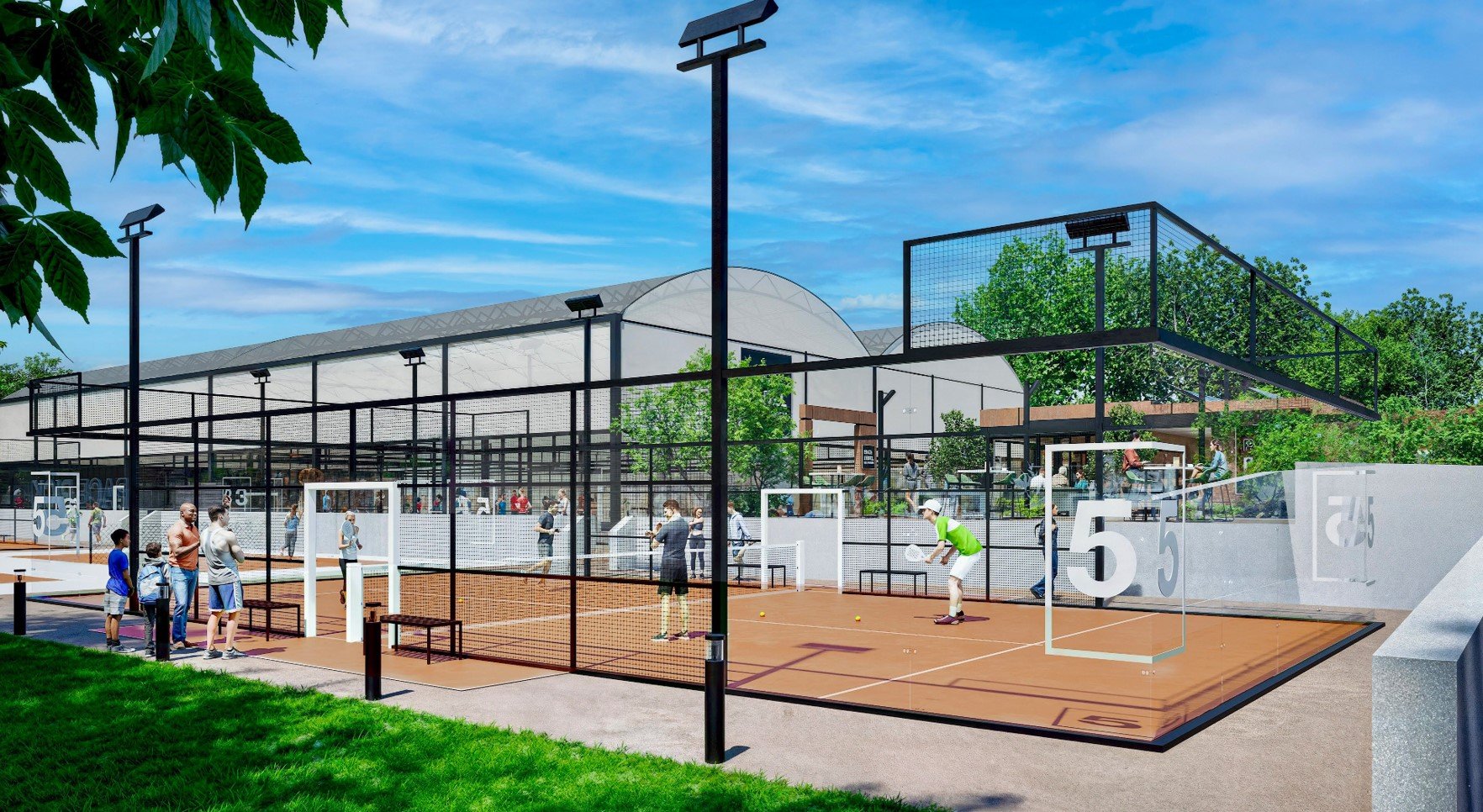 A outdoor tennis court with multiple courts, surrounded by a black metal fence. Several people are playing tennis or watching, and others are standing on the side. There are modern light poles and trees in the background, with a large building and a 