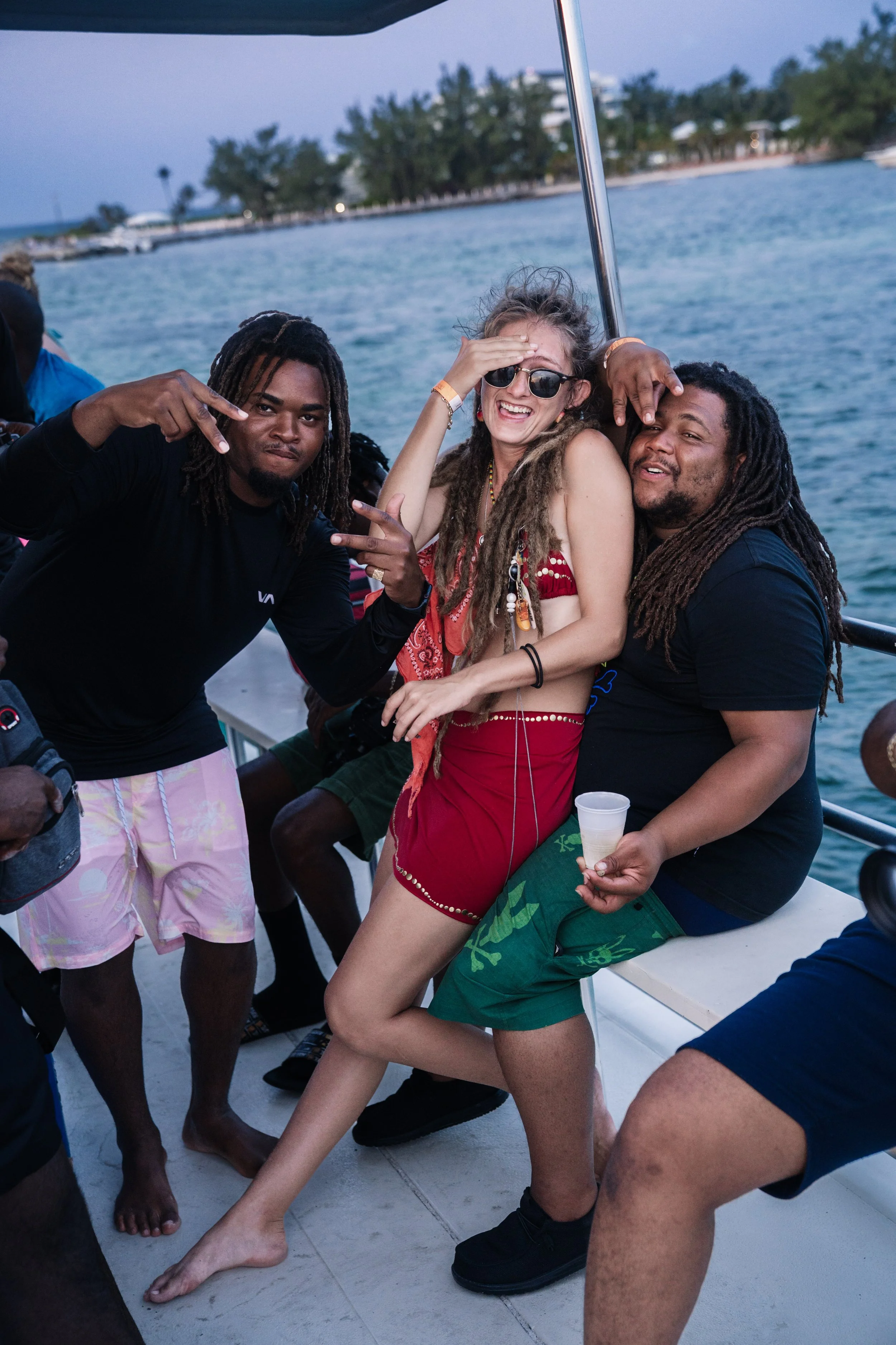 Group of friends on a boat, with water and trees in the background, enjoying a fun moment together.