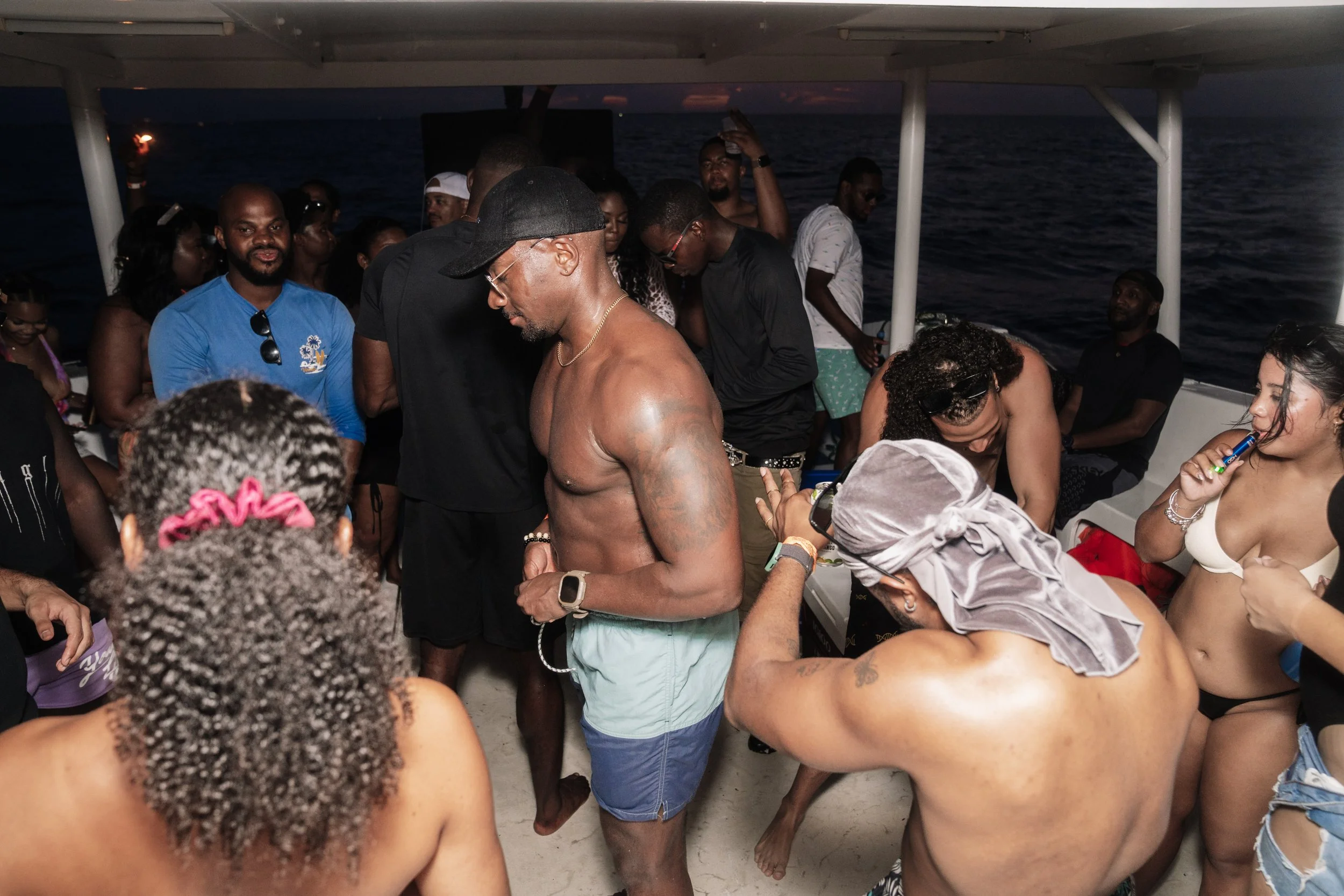 Group of people partying on a boat at night, with the ocean in the background.