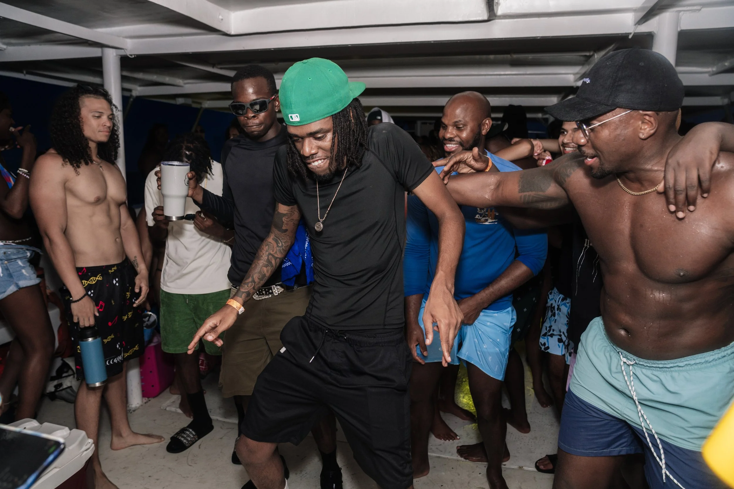 Group of people dancing and enjoying at party, some in swimwear, inside a boat or indoor space.
