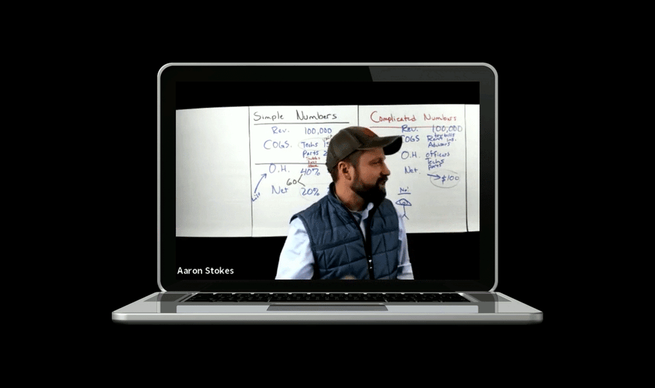 A laptop screen shows a man in a cap and vest giving a presentation about simple and complicated numbers, with handwritten notes on a whiteboard in the background.