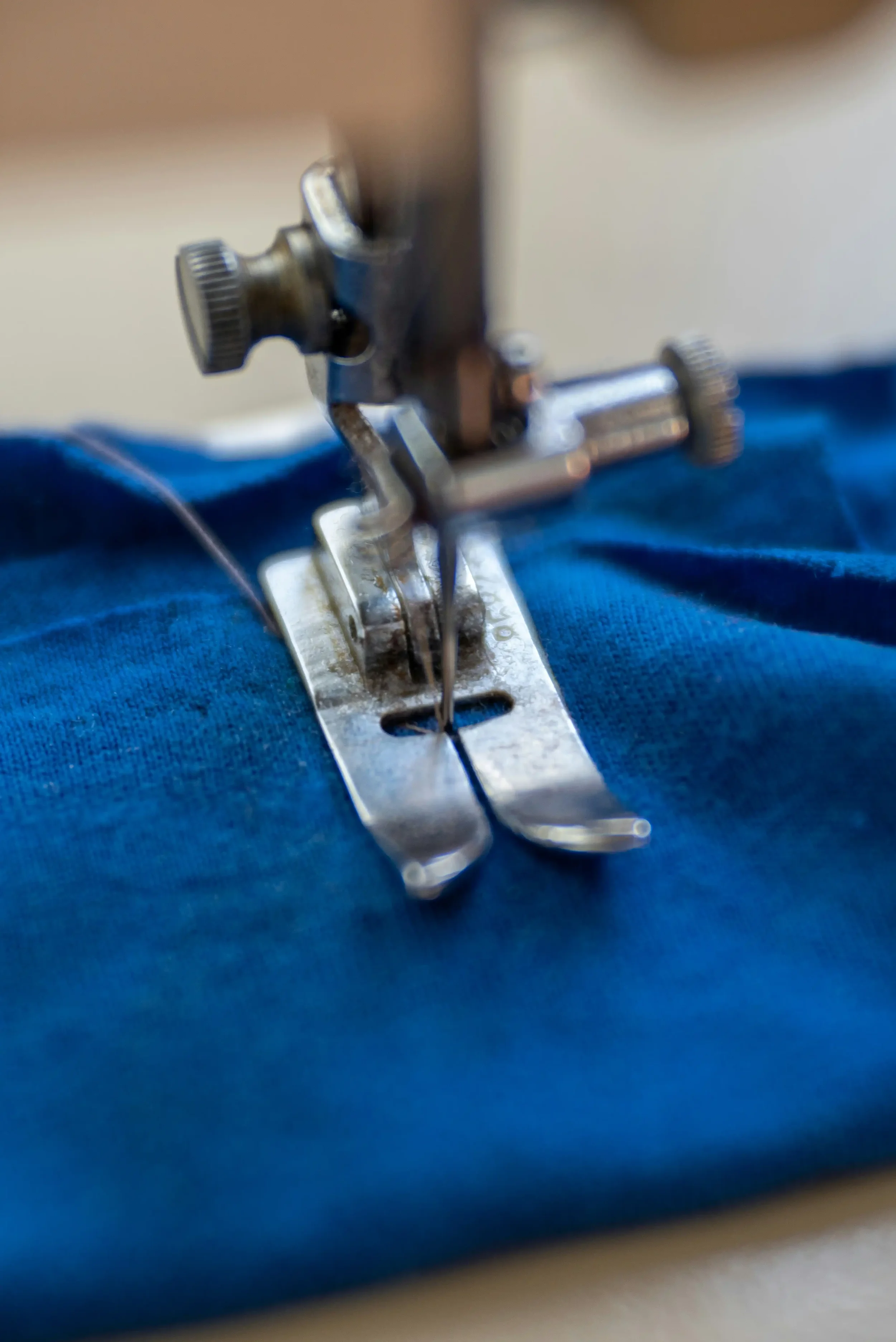Close-up of a sewing machine needle stitching blue fabric.