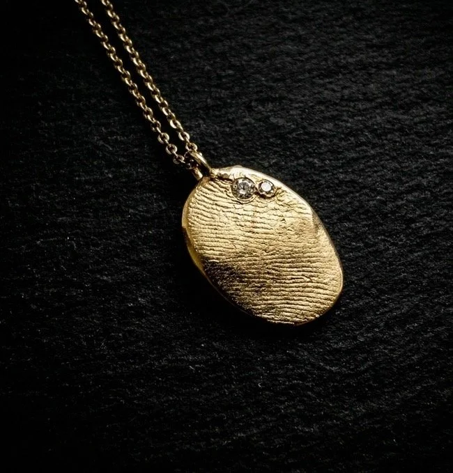 A fathers fingerprint with 3 stones to represent a step mom and his two kids. A lasting talisman after his passing.  14K