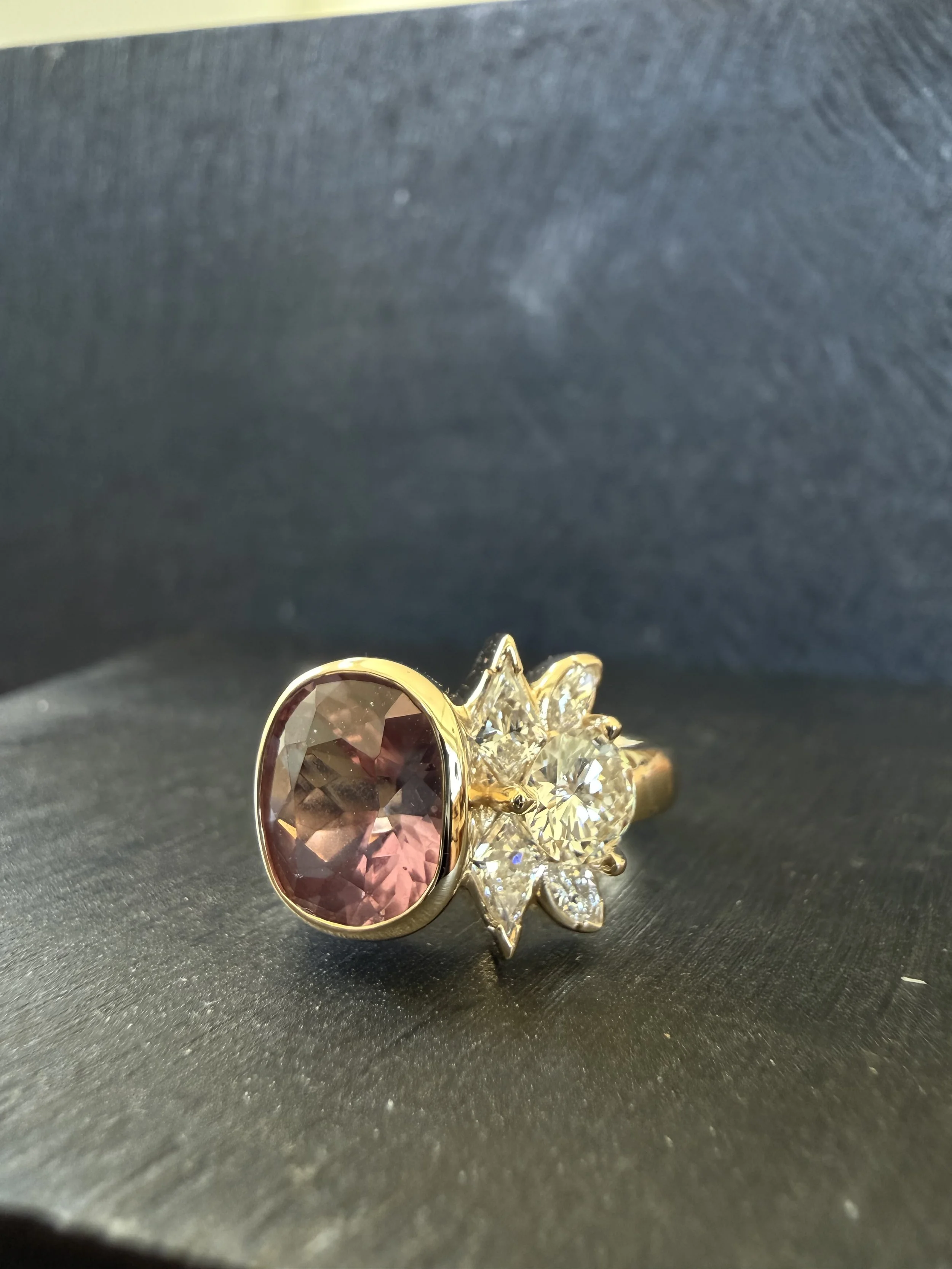 A sapphire sourched from a woman owned mine with heirloom and new diamonds. 14K