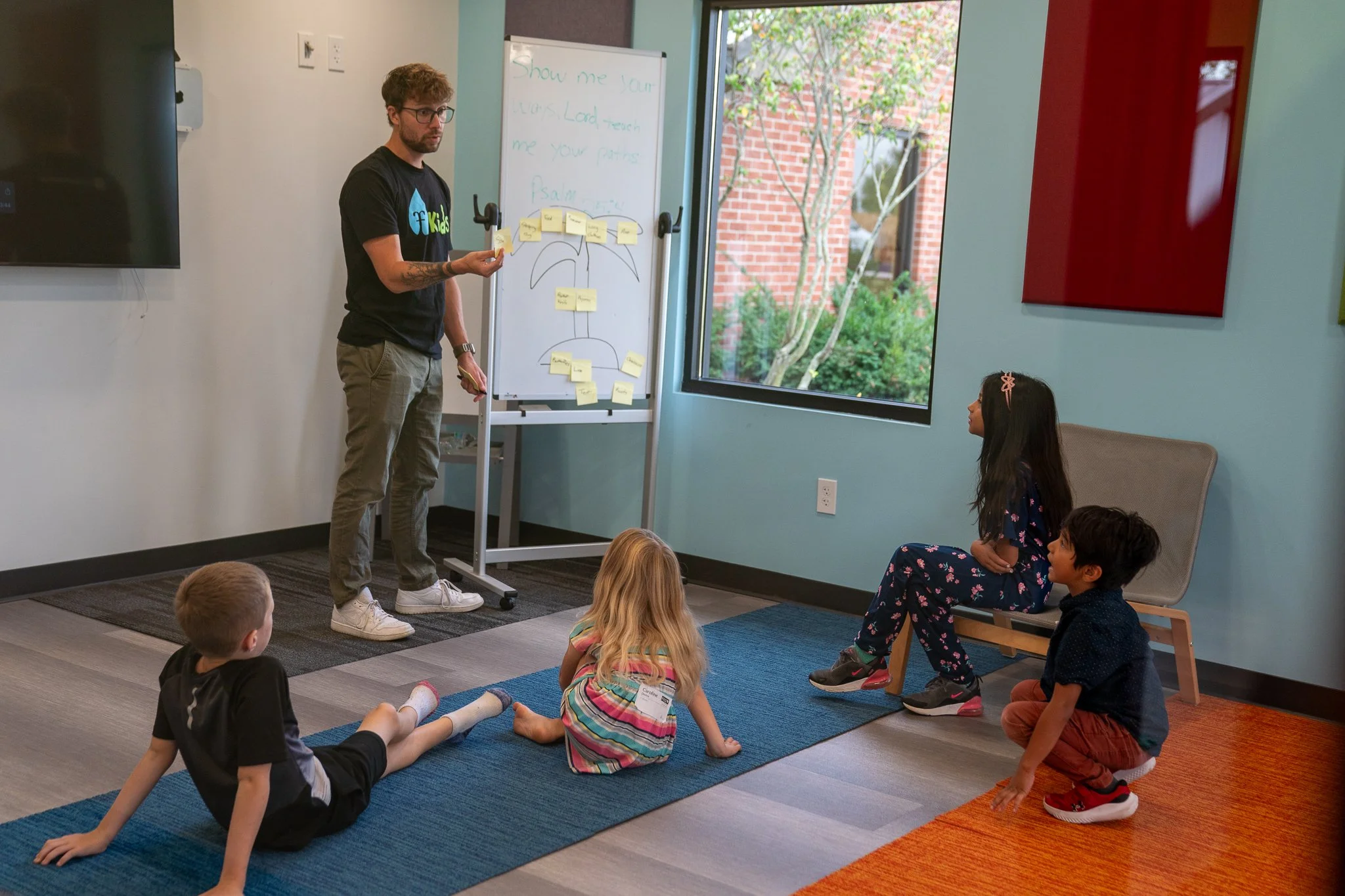 Children sitting on the floor while a teacher leads a Bible lesson using a whiteboard at The Fountain’s Sunday morning Fountain Kids program for K–4th grade. Interactive, Christ-centered learning environment in Fountaintown, Indiana.