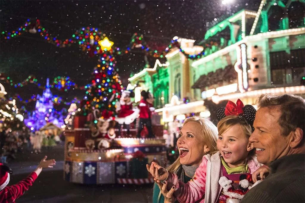 Family enjoying glowing Christmas decorations and a large holiday tree during a Disney vacation.