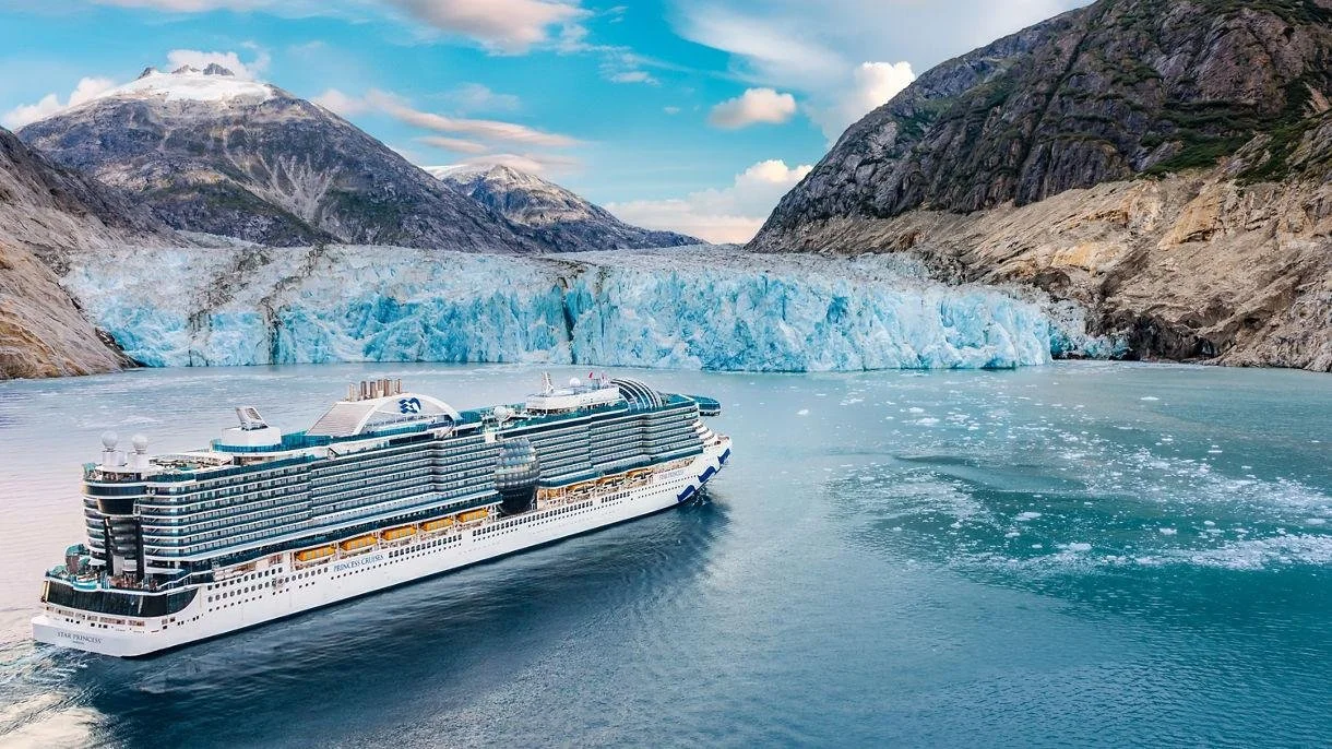 Princess cruise ship sailing through Alaska with a glacier and snow-covered mountains in the background.