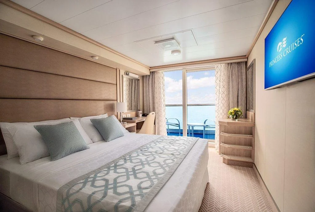 Princess Cruises balcony stateroom with a comfortable bed and private outdoor seating.