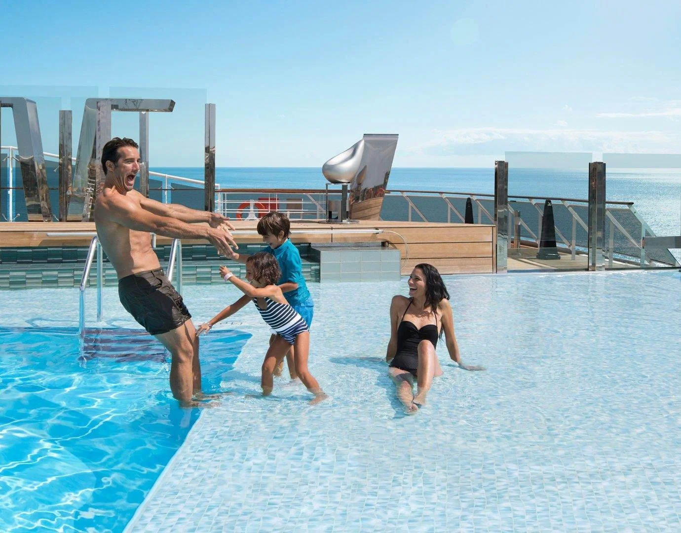 Parents and children relaxing beside a pool on a cruise ship.