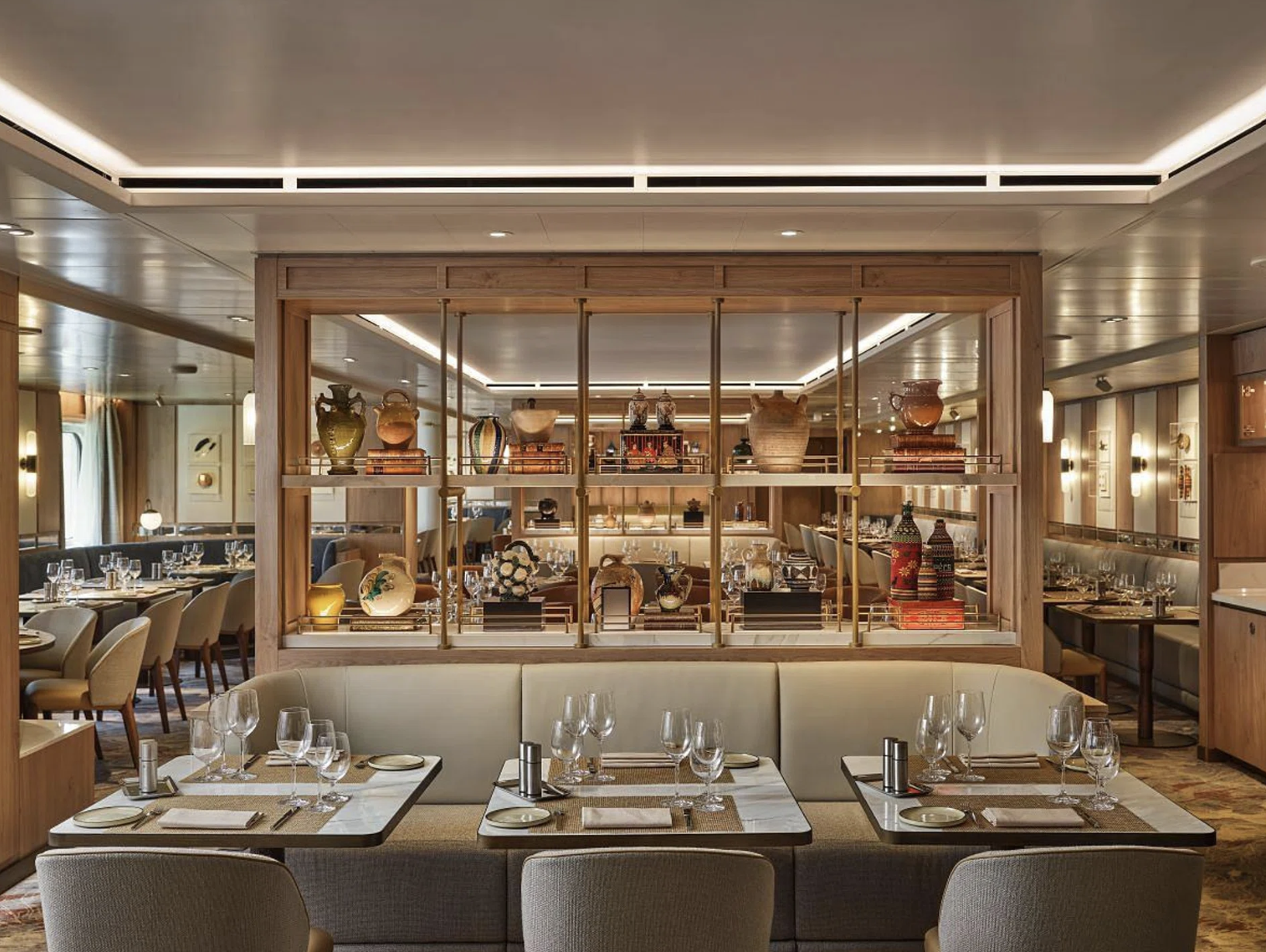 Silversea S.A.L.T. dining room with upholstered seating, set tables, and a central display of pottery and books.