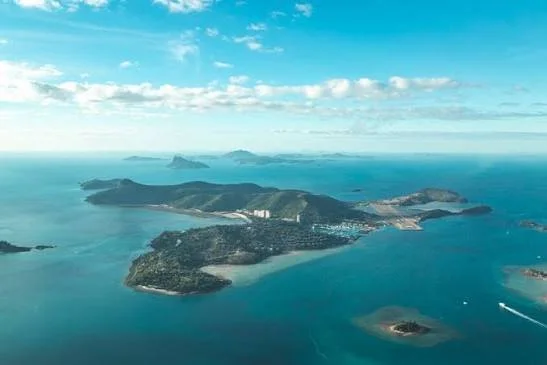 Aerial view of Hamilton Island surrounded by the turquoise waters and smaller islands of the Whitsundays in Queensland, Australia.