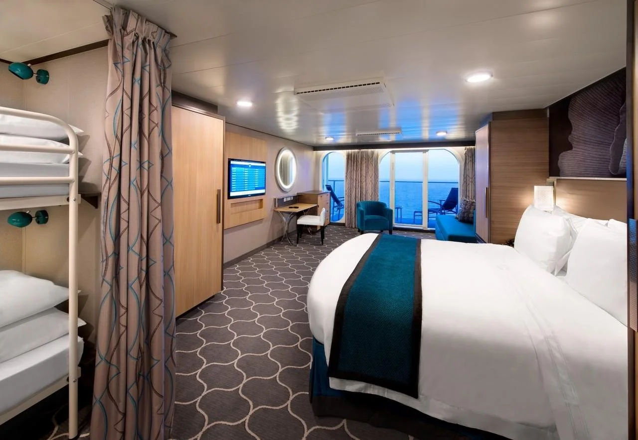 Cruise stateroom showing beds, seating, and space for a family’s luggage.