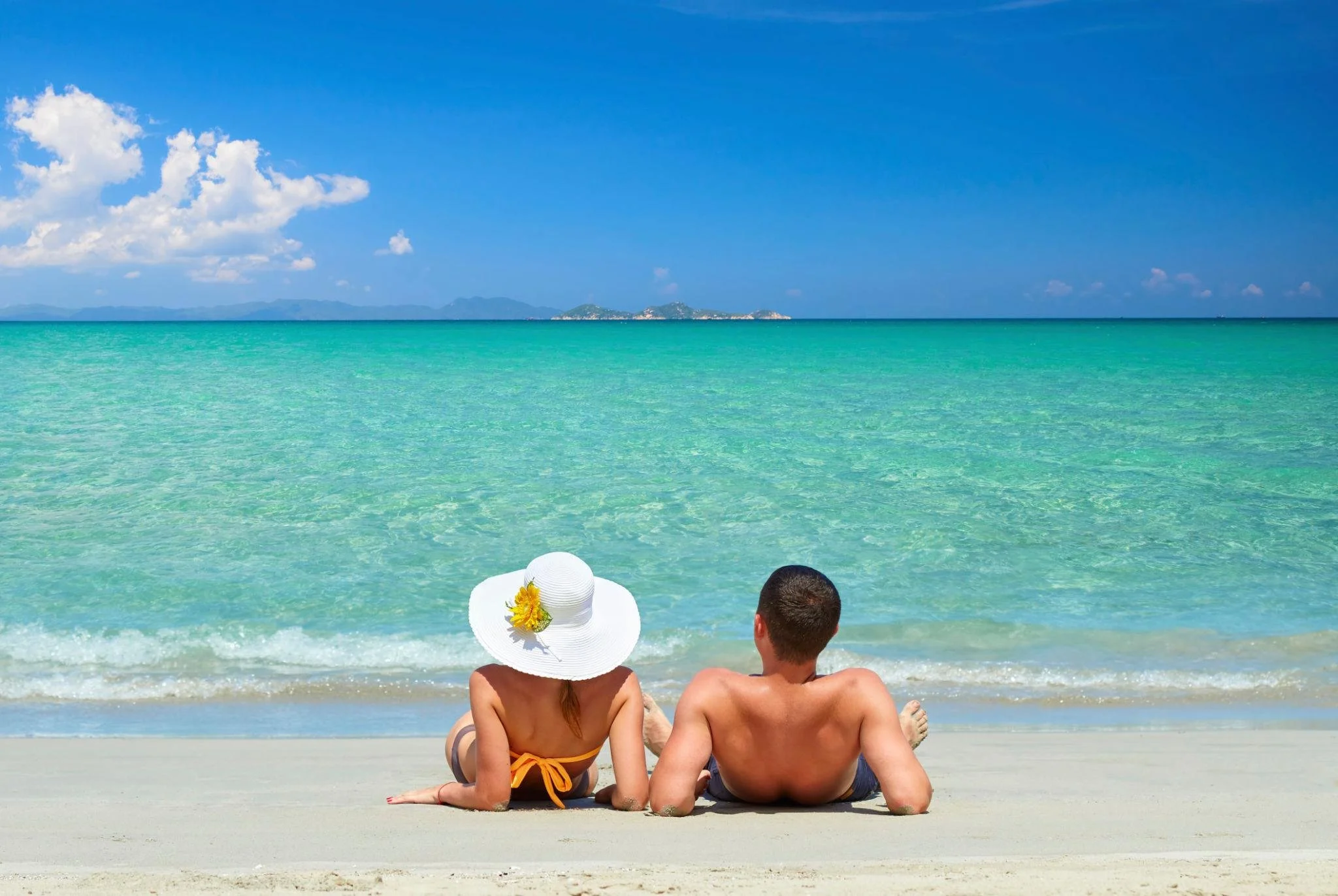 Couple relaxing beside the ocean during a beach vacation.
