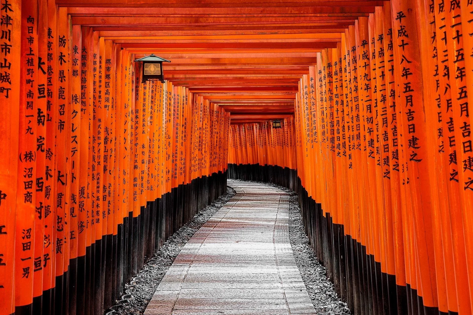 A pathway lined with traditional orange torii gates at Fushimi Inari Shrine in Kyoto.