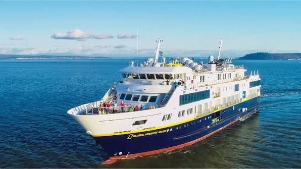 A large white and blue passenger ferry boat sailing in the water.