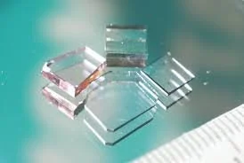 Several transparent glass or acrylic cubes on a reflective surface with a teal background.