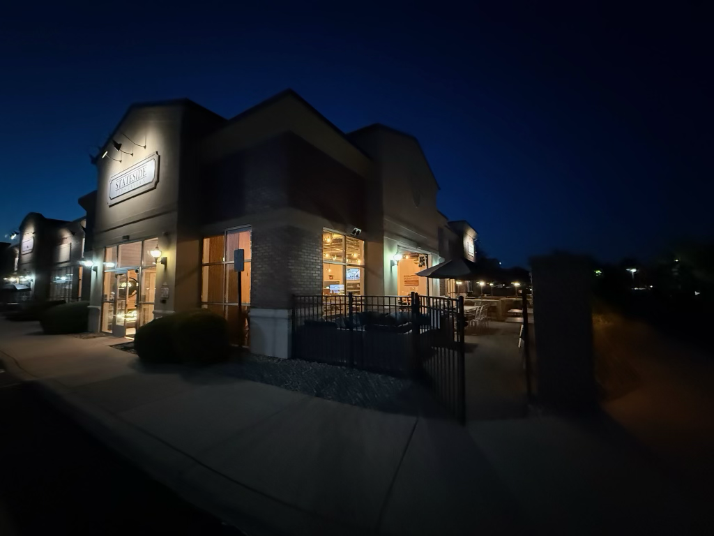 A restaurant called 'Stallside' illuminated at night, with outdoor seating and a black metal fence.