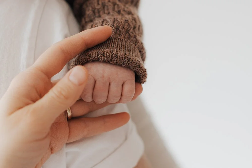 Babyhand greift Finger von Mutter, Detailaufnahme