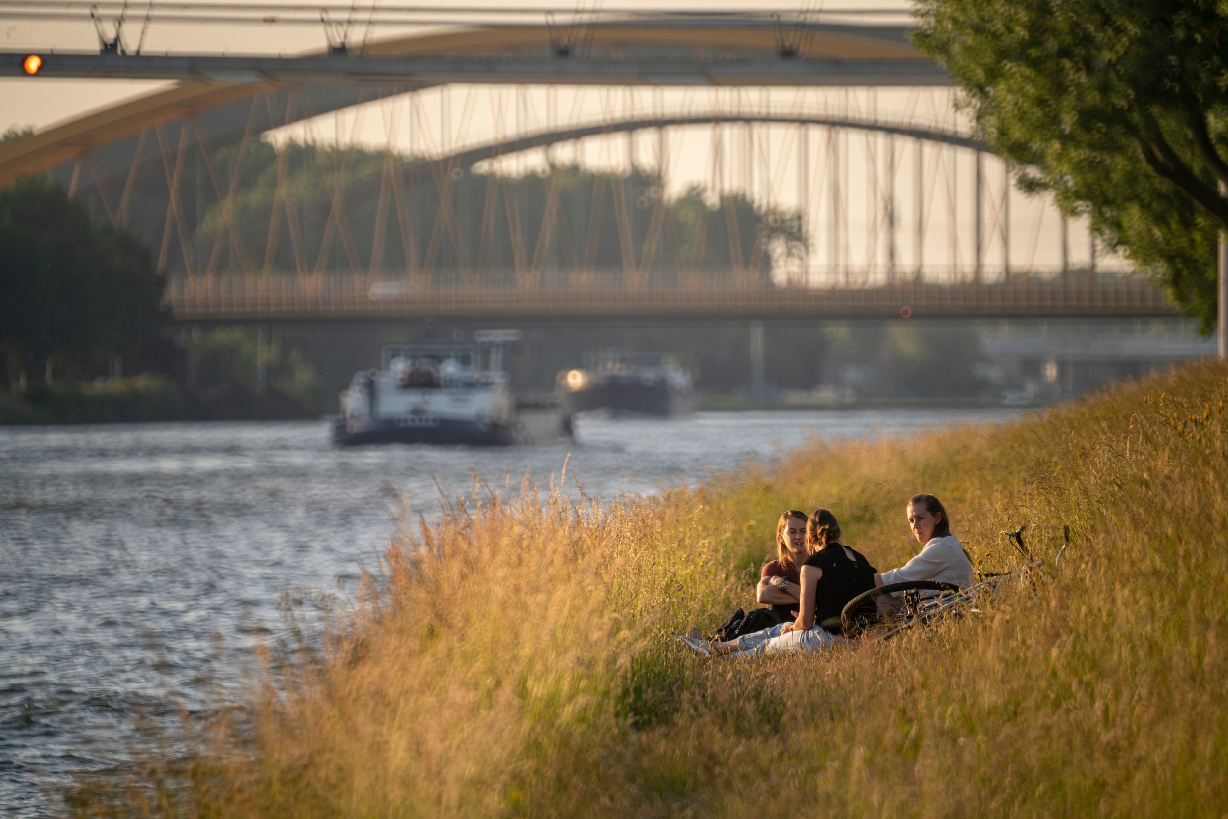 youngsters-relaxing-on-the-grassy-canal-shore-on-a-2024-09-30-20-16-09-utc.jpg