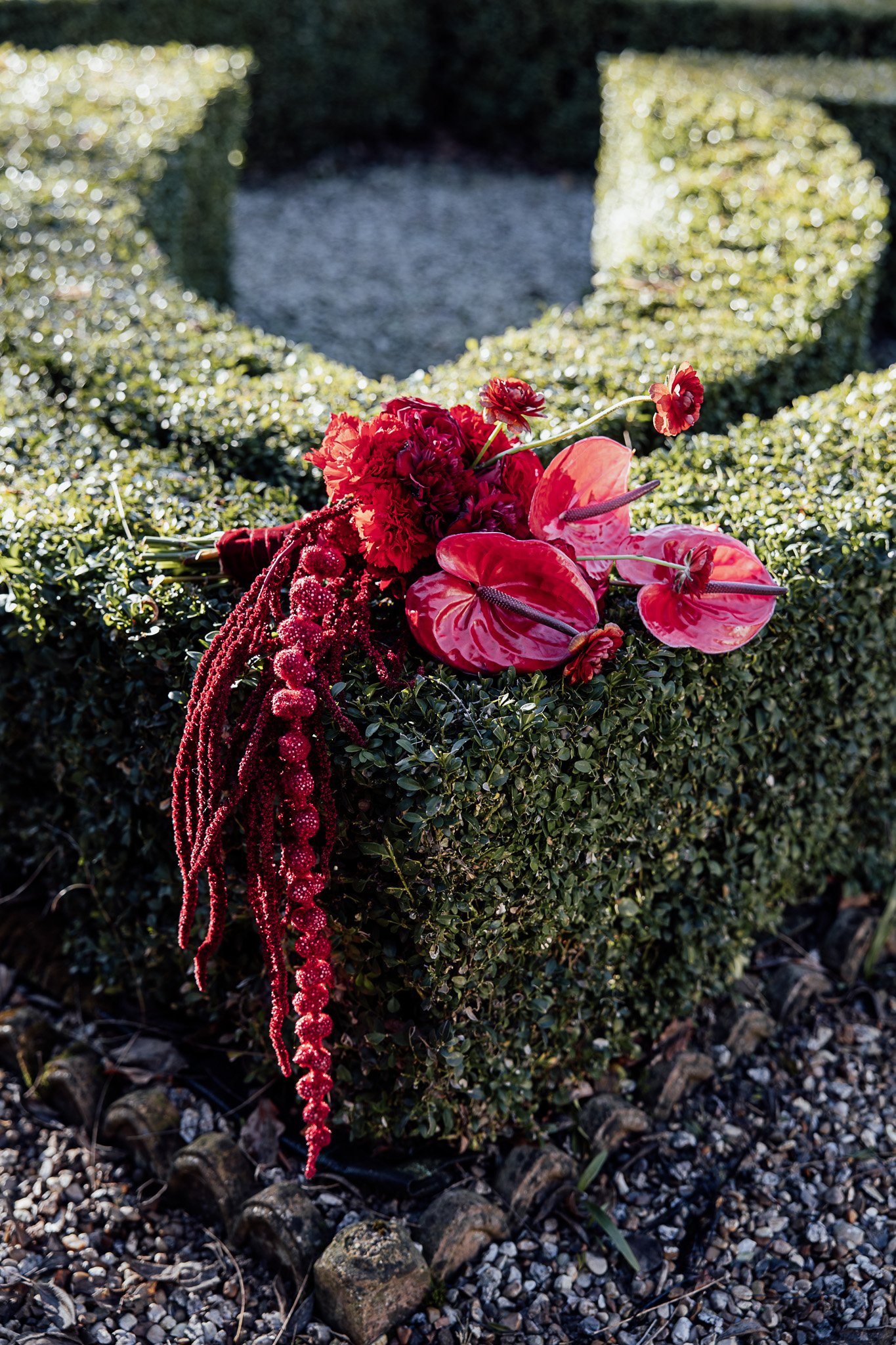 Red floral installation styled on garden feature at Byre Barn Kent wedding venue