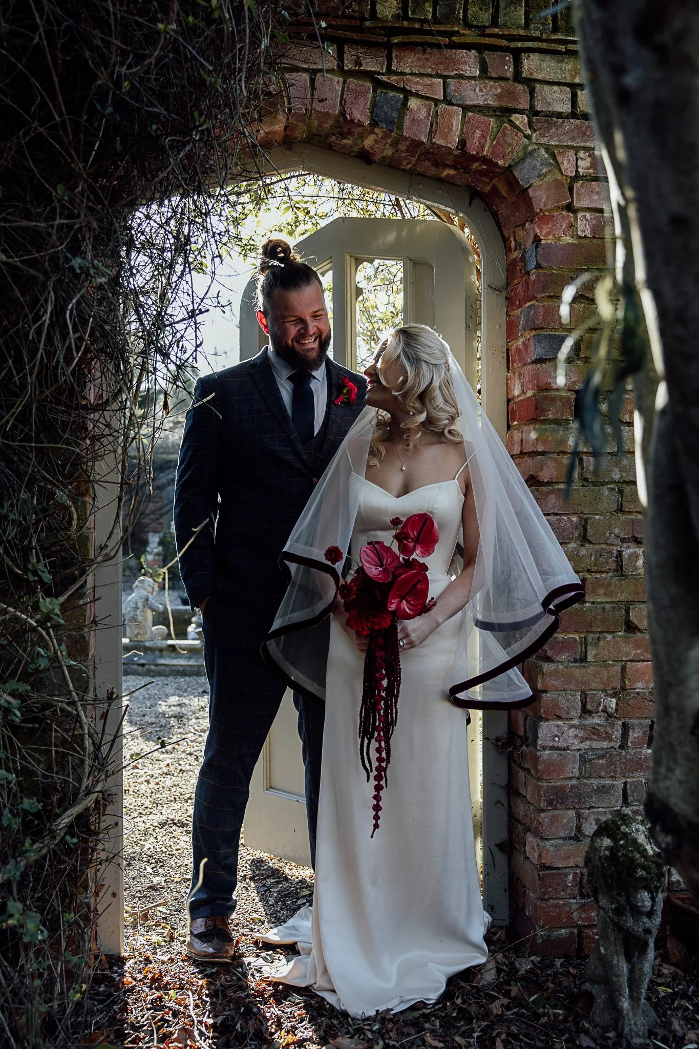 Bride and groom walking through stone archway at Byre Barn Kent wedding venue