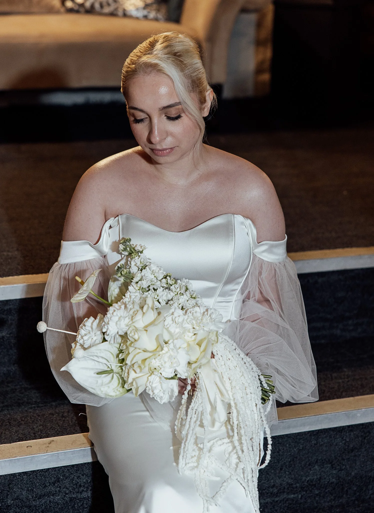 Bride holding a soft white wedding bouquet featuring elegant, seasonal floral design.