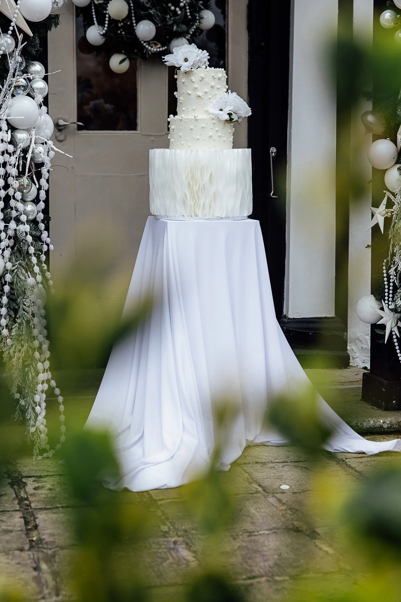 Wedding cake styled at The Orchard wedding venue, featuring elegant white detailing and soft draping.