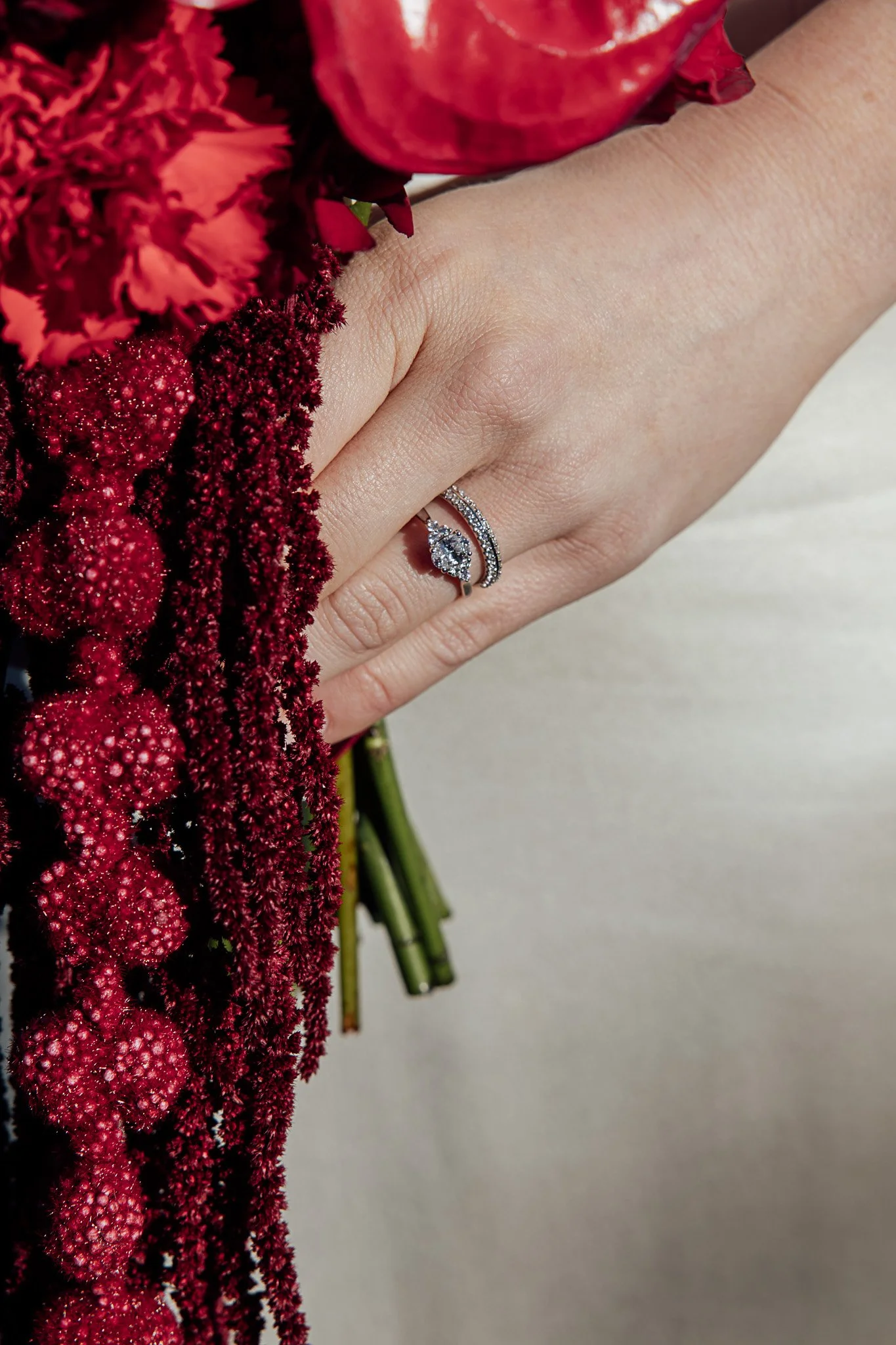 Wedding ring detail with cascading red florals at Byre Barn Kent styled shoot