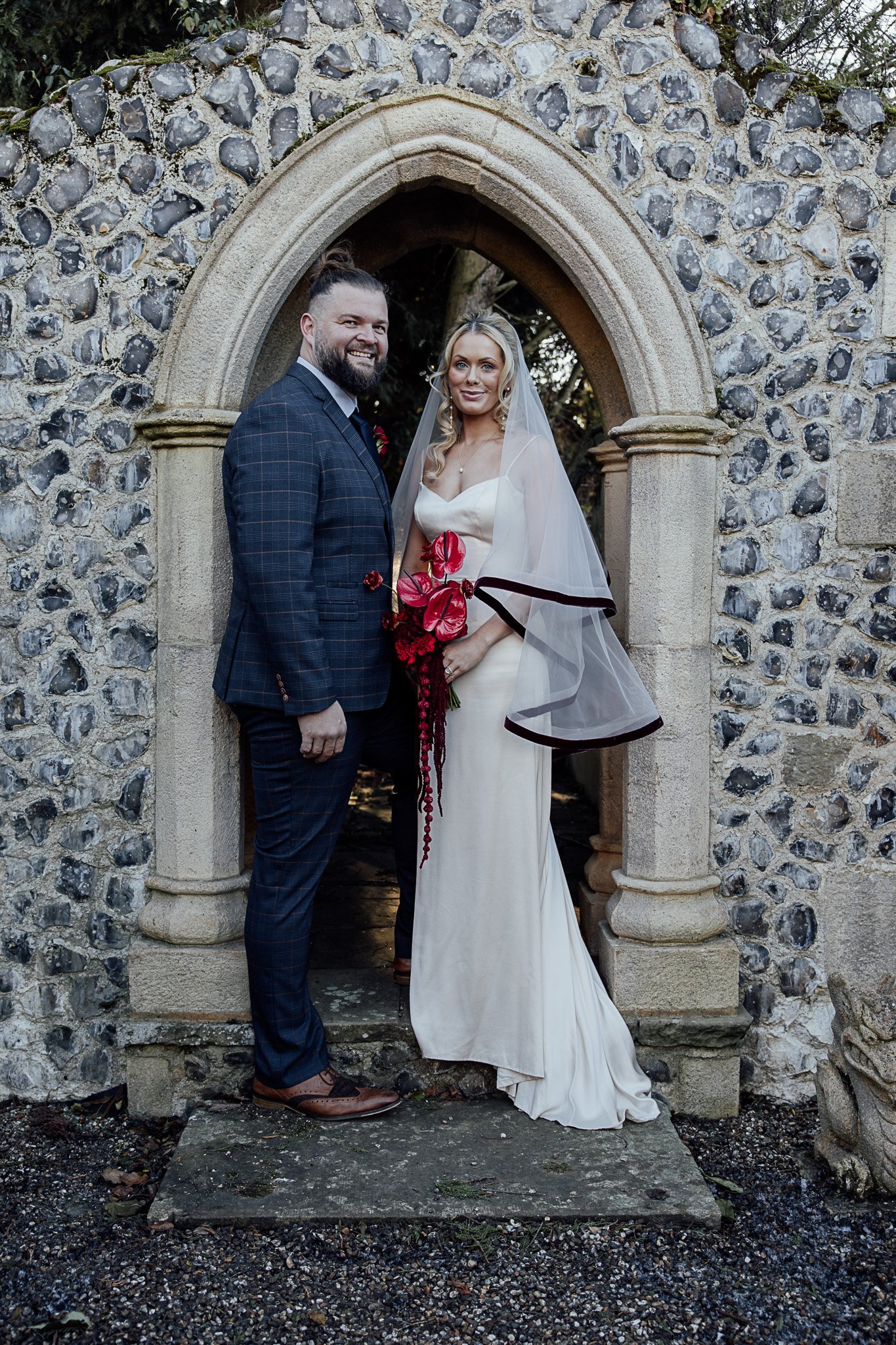 Bride and groom portrait beneath stone archway at Byre Barn Kent wedding venue