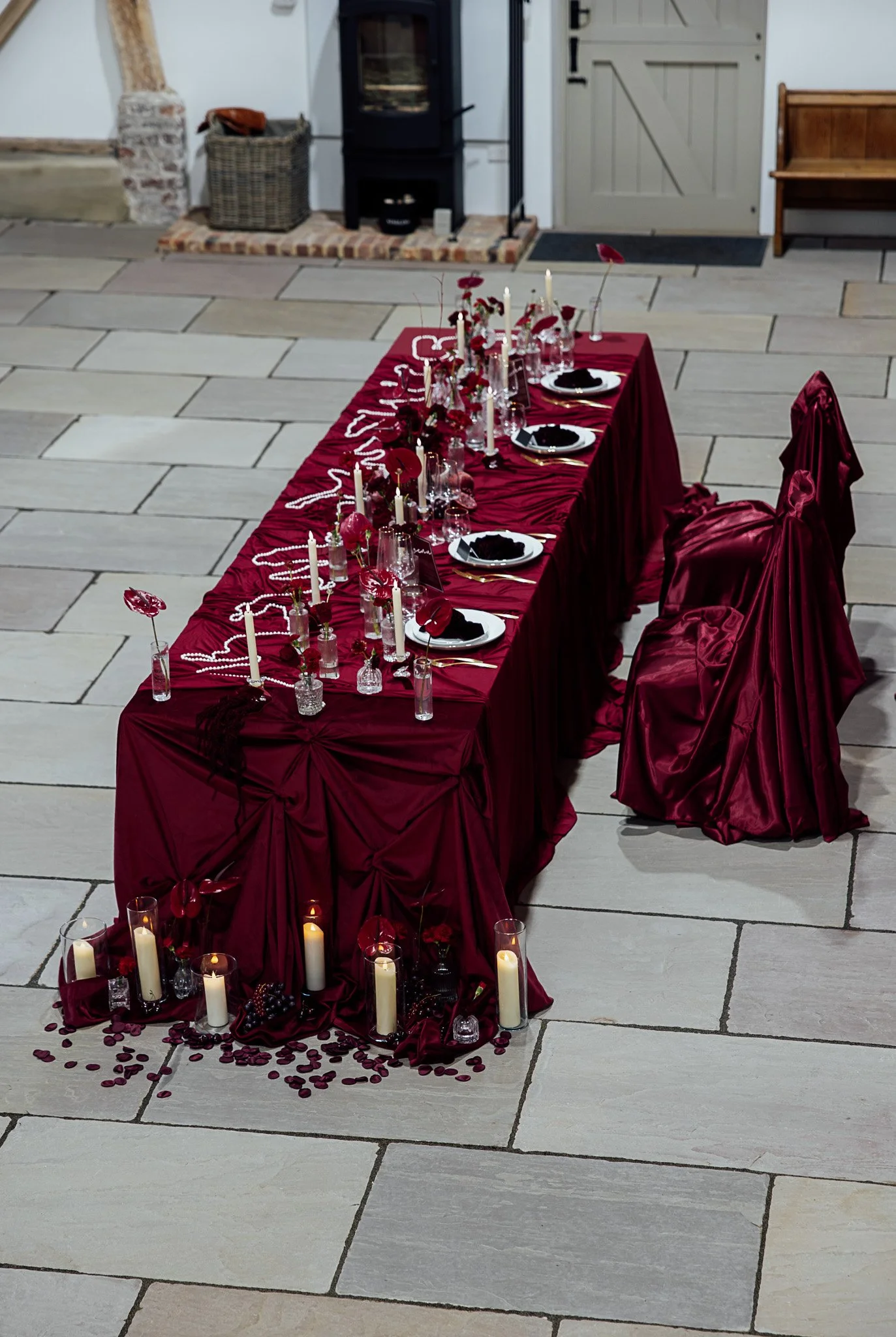 Long banquet wedding table styled in rich red tones at Byre Barn Kent venue