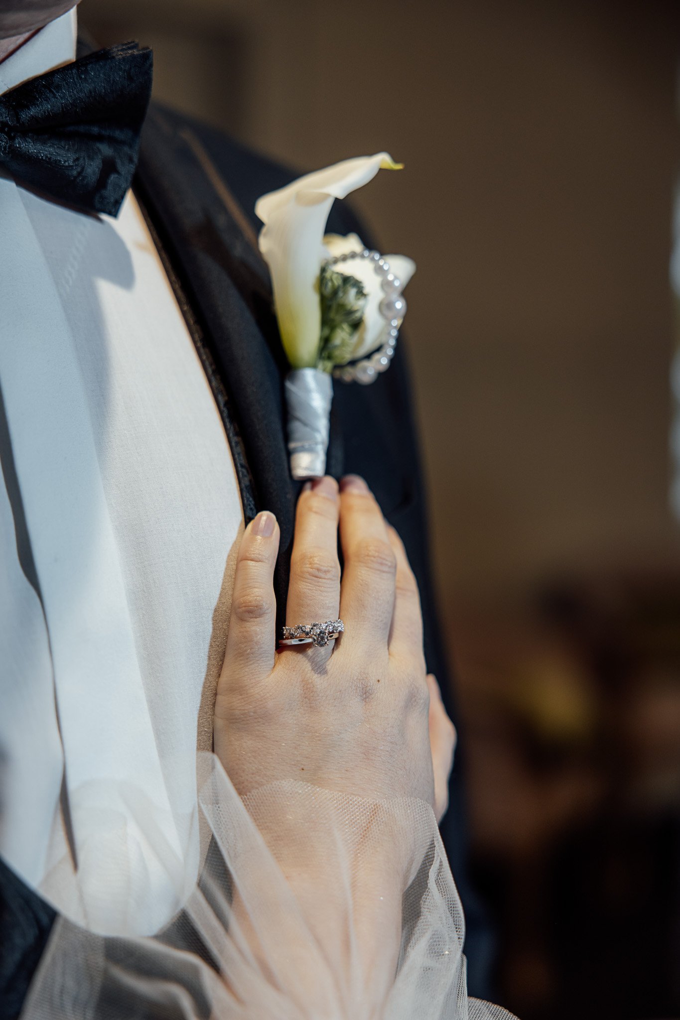 Wedding ring detail styled with a groom’s suit and white floral boutonniere at a Kent wedding shoot.