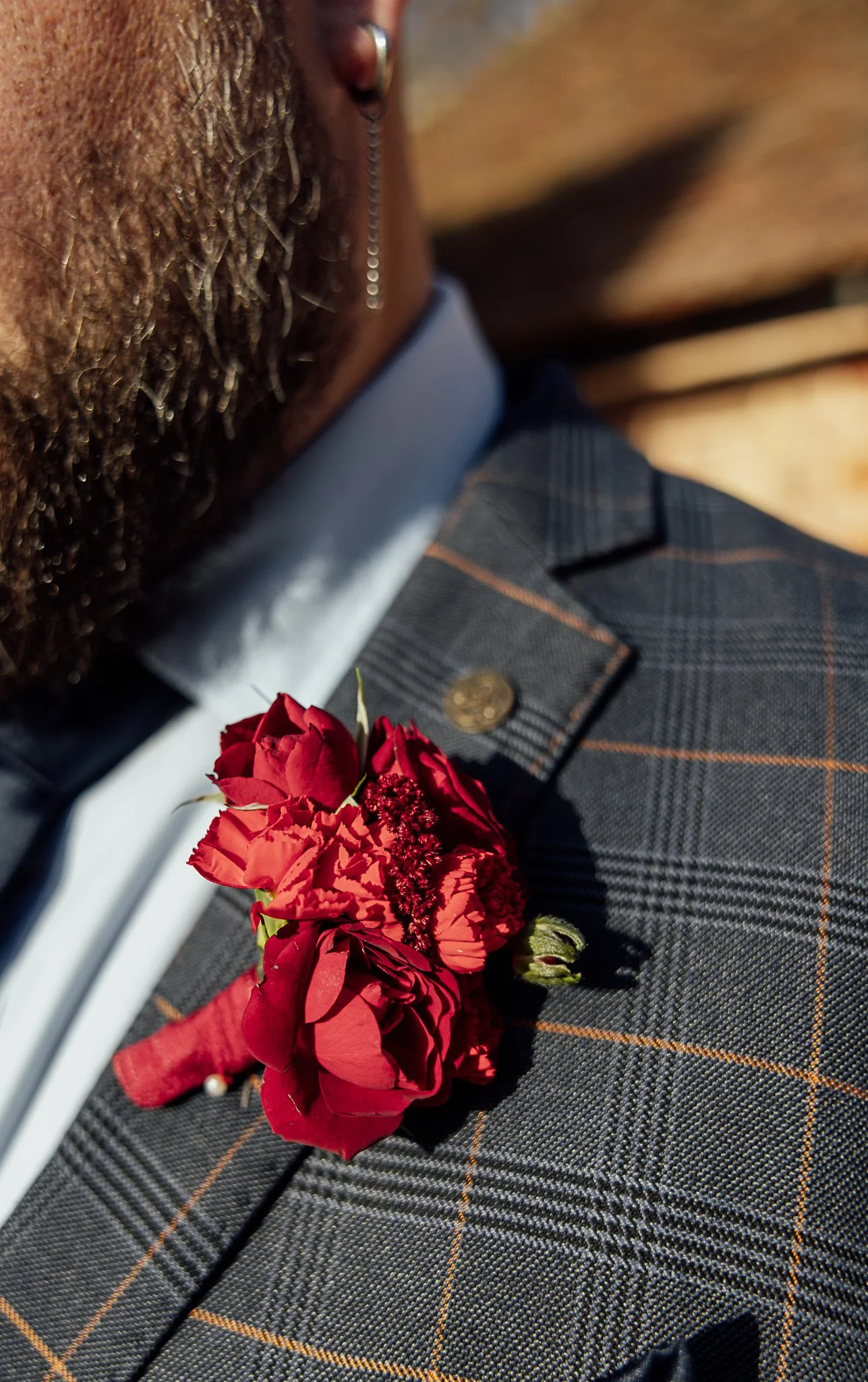 Groom boutonniere with red florals on tailored suit at Byre Barn Kent wedding
