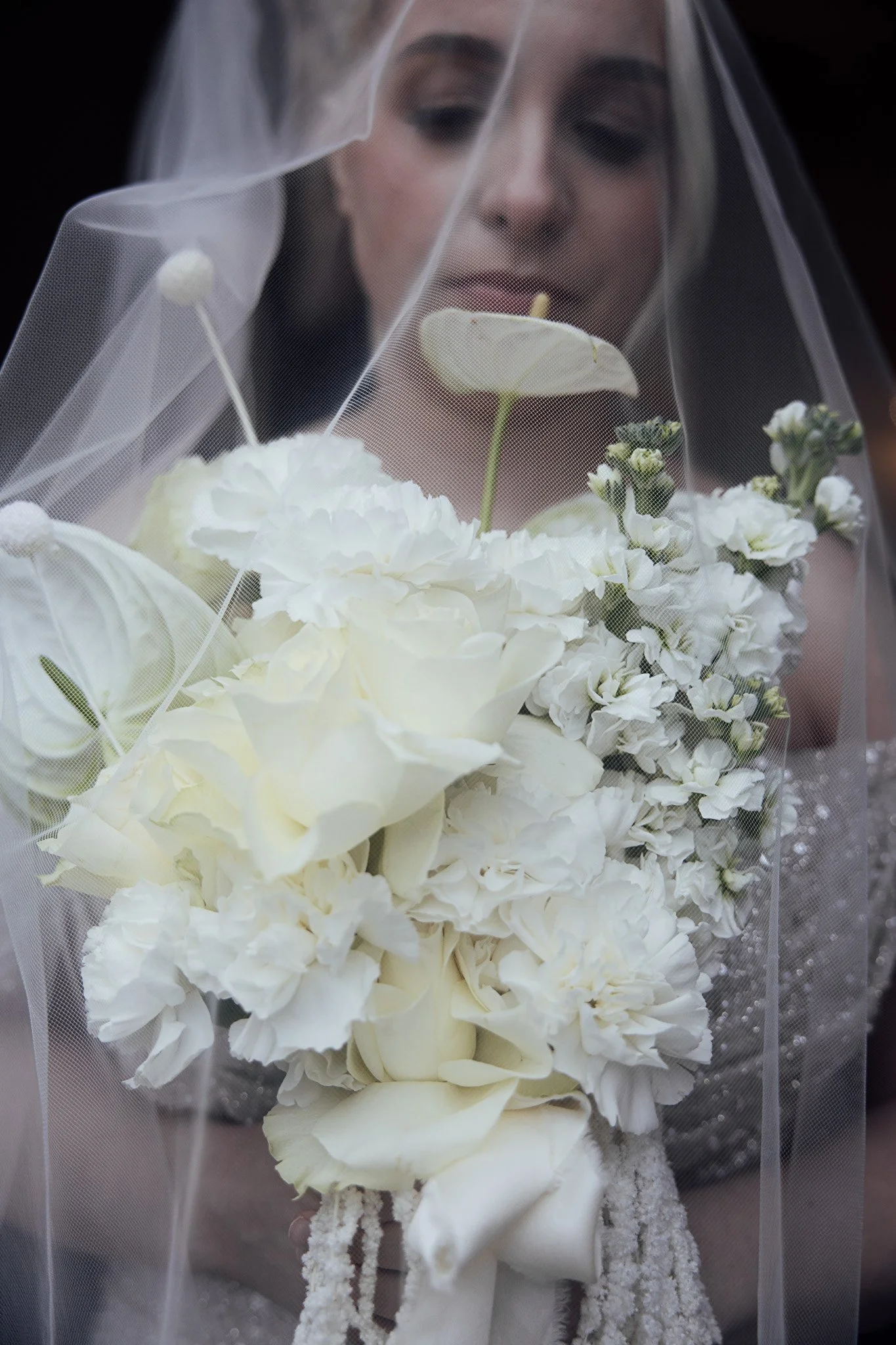 Romantic bridal bouquet styled beneath a veil, showcasing soft white wedding flowers.