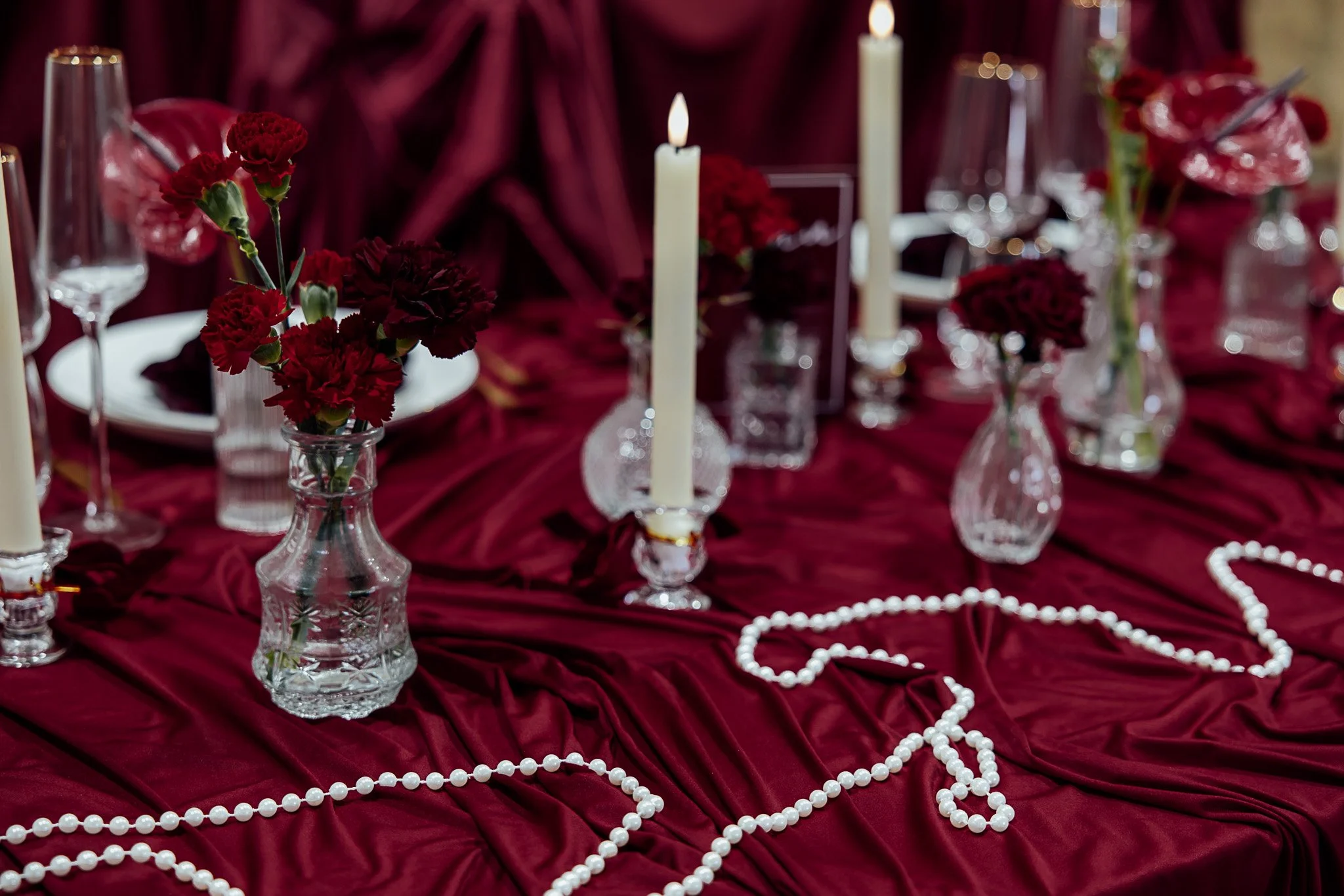 Elegant candlelit wedding table styling with red linens at Byre Barn Kent