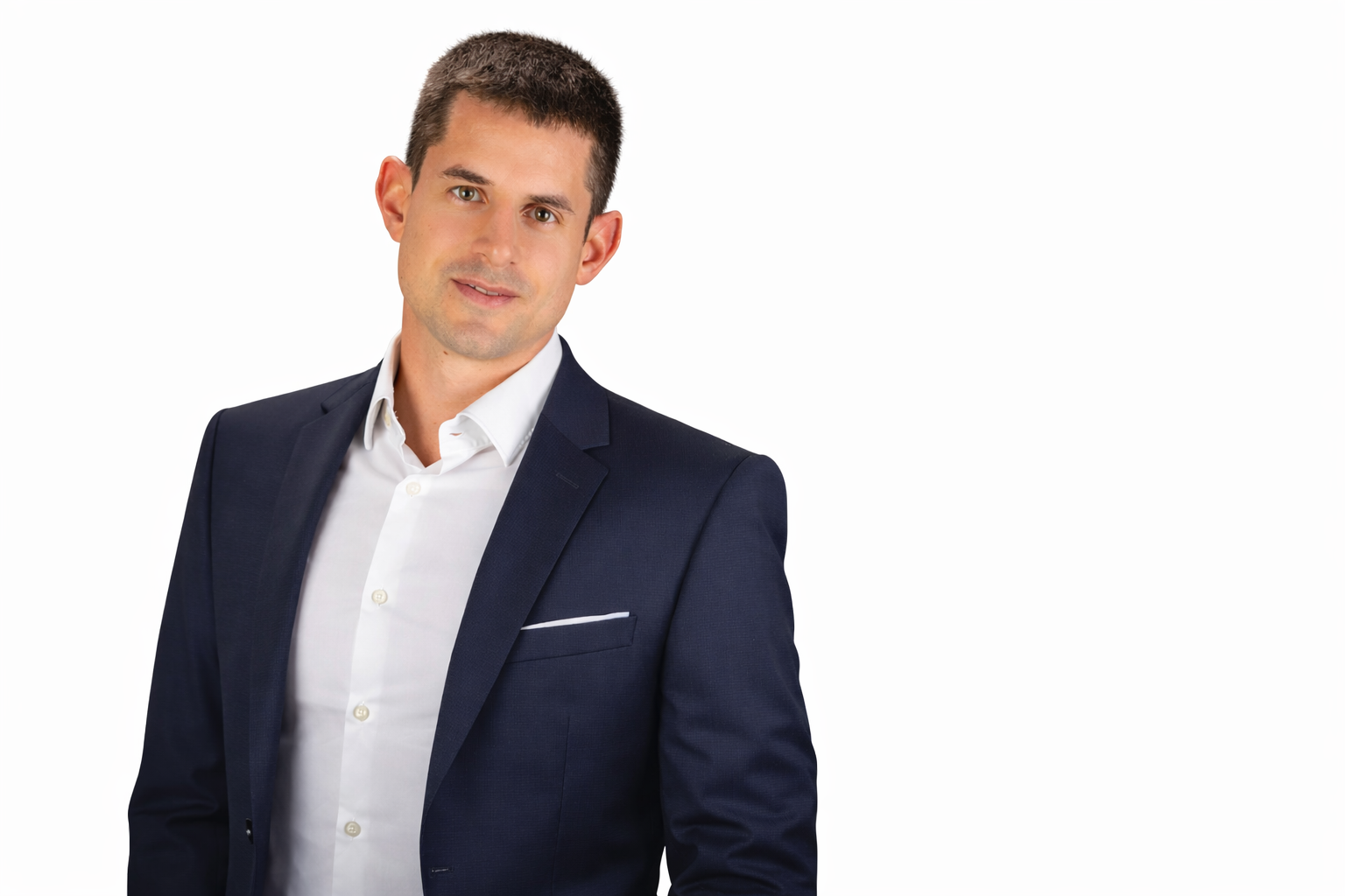 A young man wearing a dark suit jacket and white dress shirt, posing against a white background.