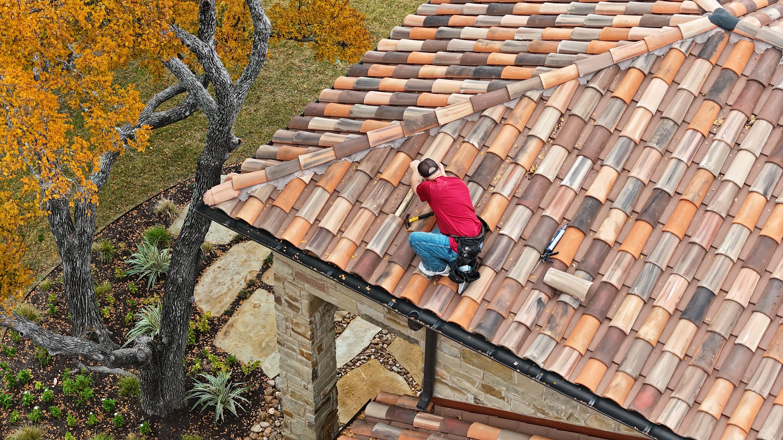 Close-up of white vertical siding on a building with a metal roof, shadows cast on the wall, and trees in the background.