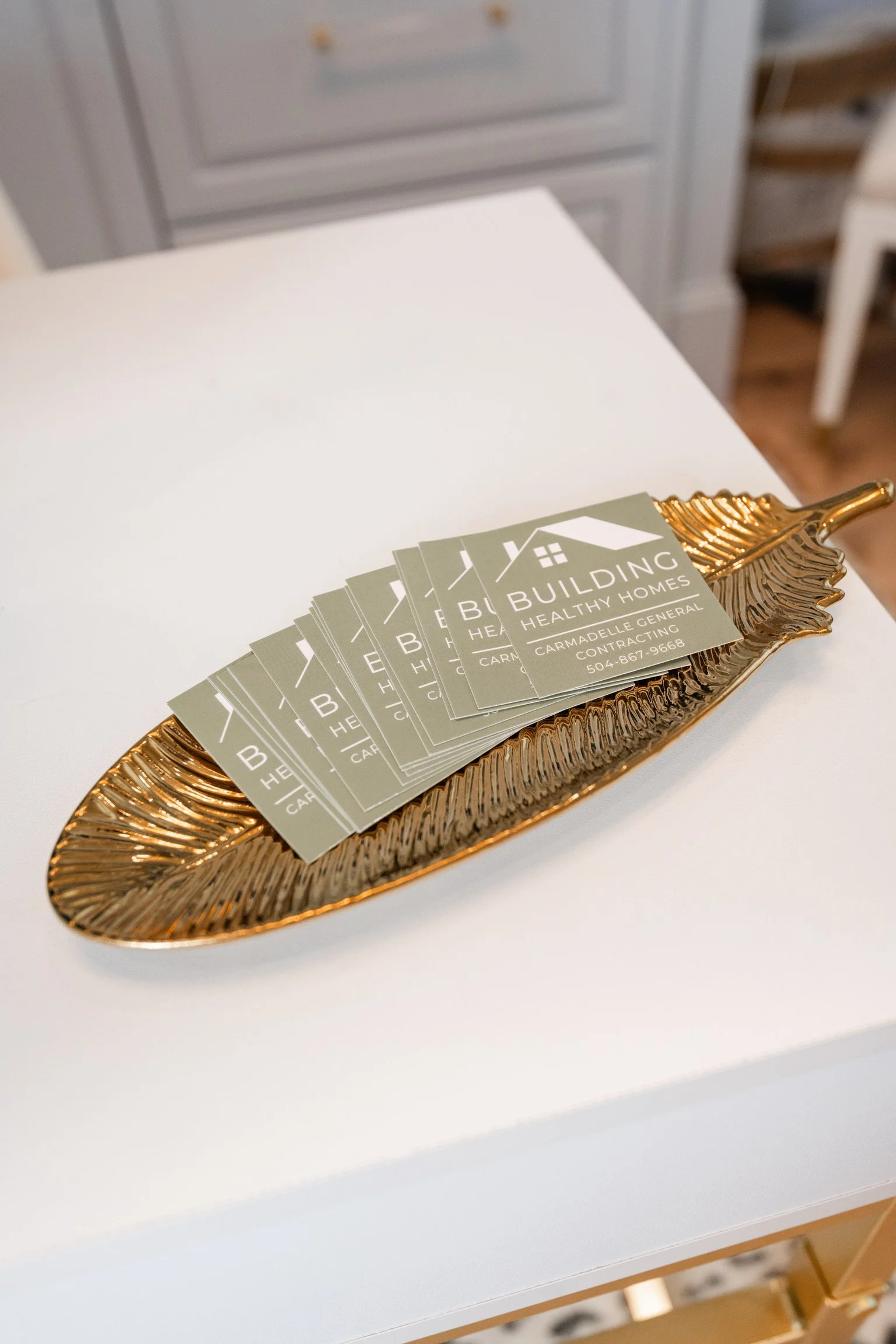 Business cards for 'Building Healthy Homes' on a decorative gold tray.