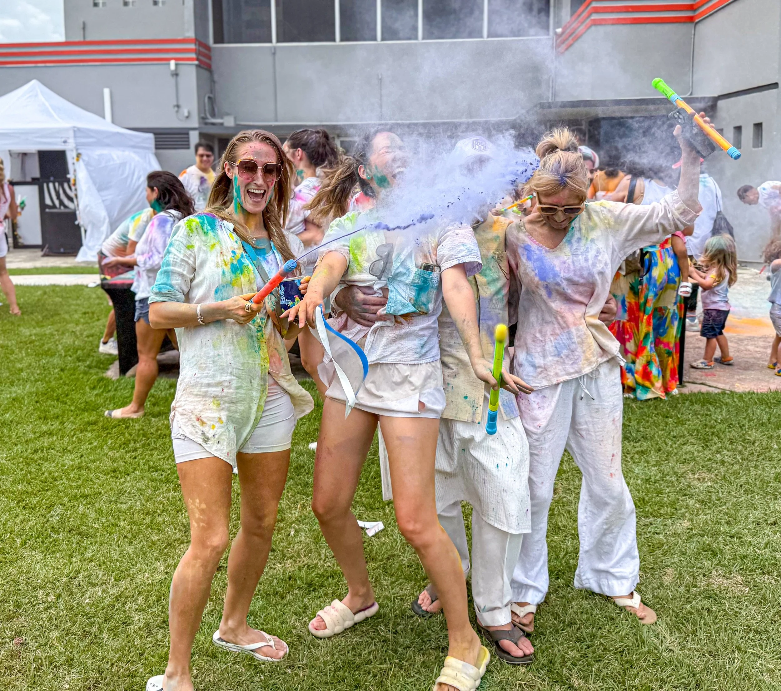People celebrating at a color powder festival, smiling and throwing colorful powder at each other.