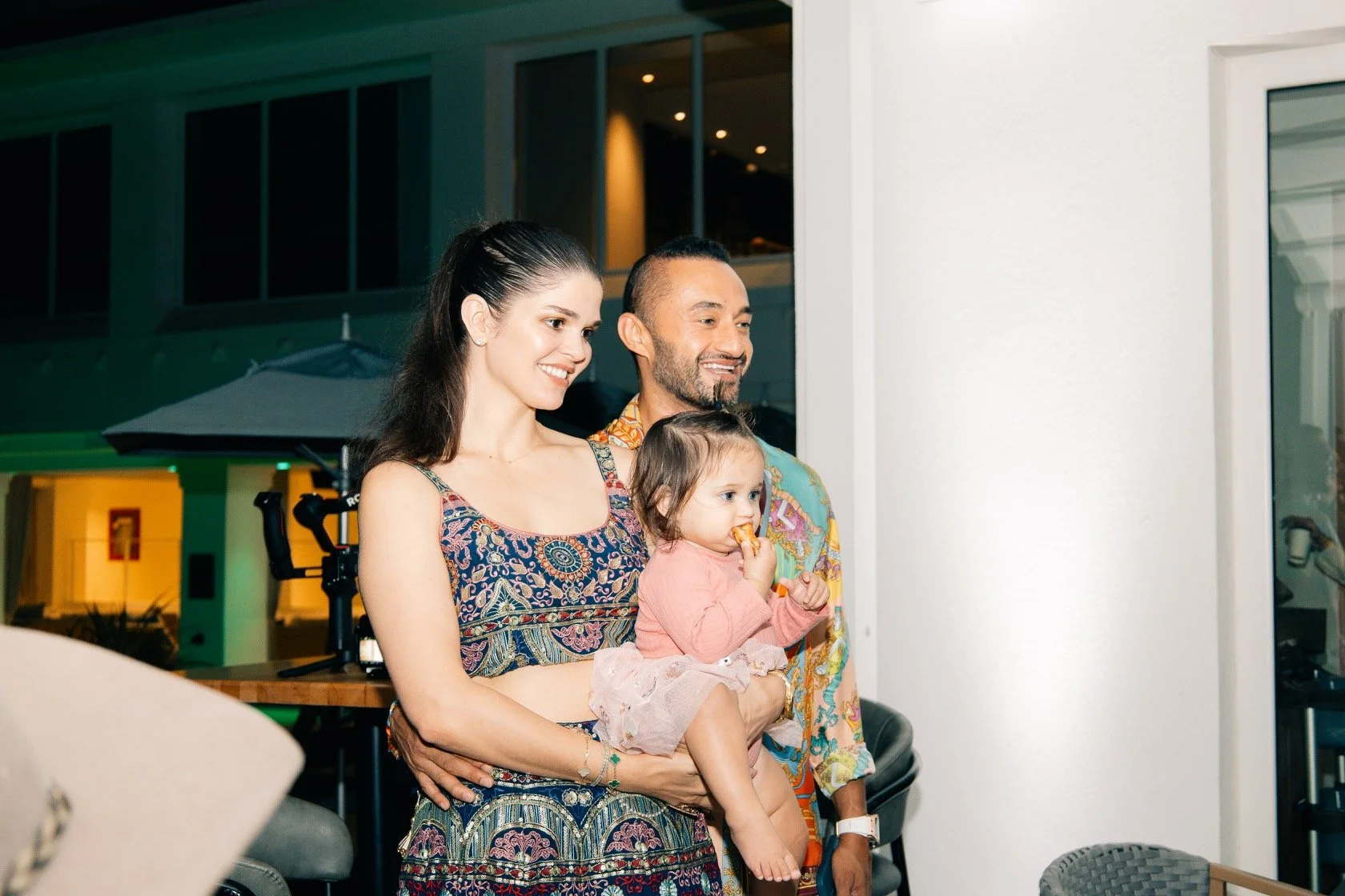 A young woman, a man, and a little girl are watching something on a screen together.