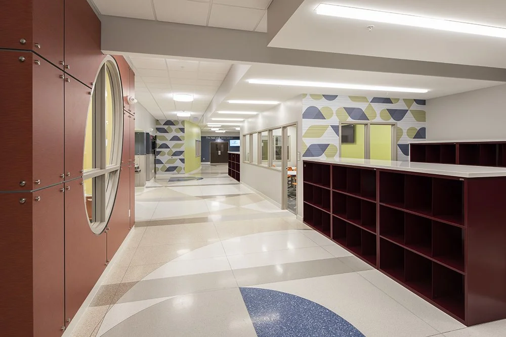 Empty hallway in a modern building with colorful walls, large red shelving units, and circular and geometric wall patterns.