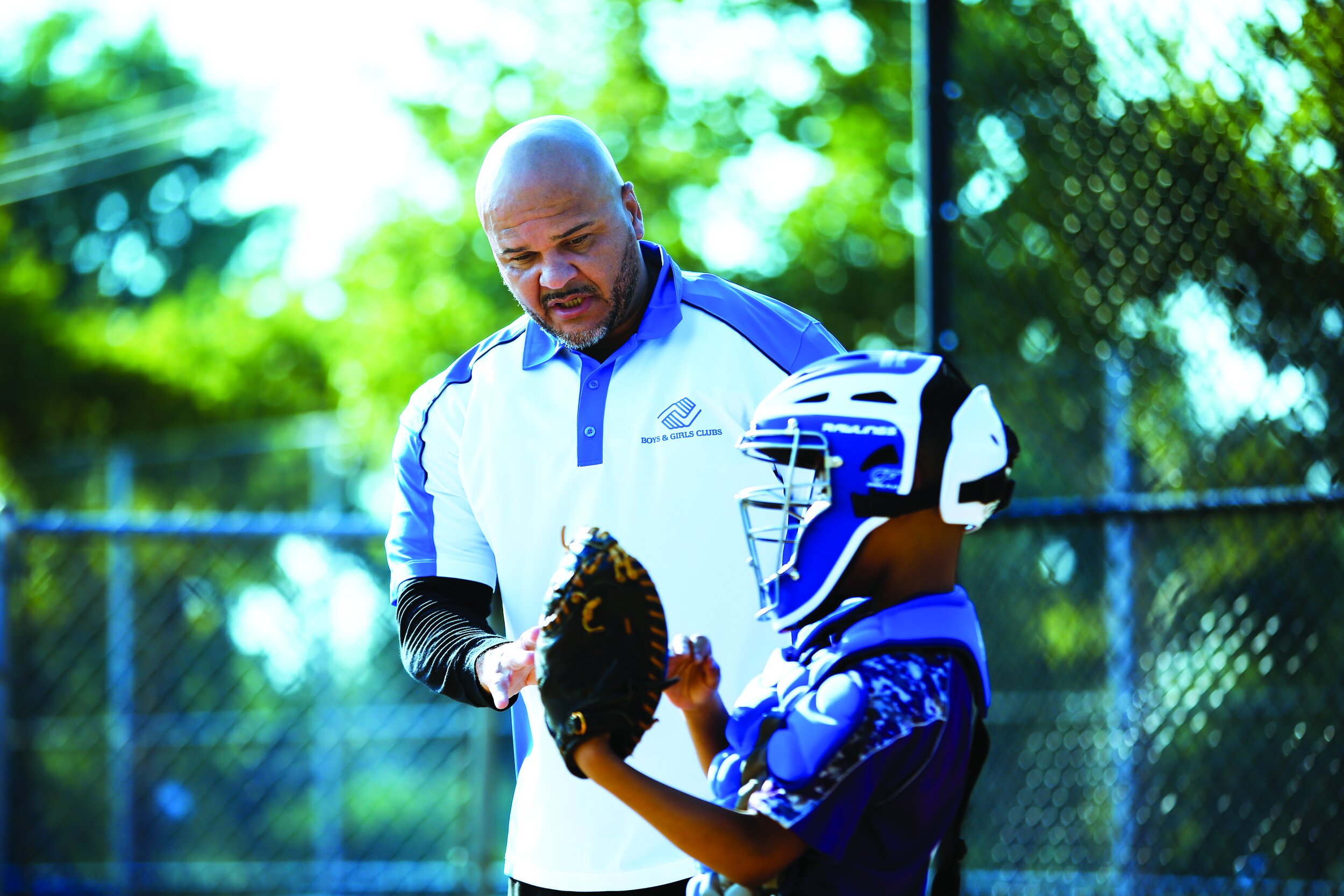 A coach and a young baseball player having a discussion during practice or game at outdoor field.