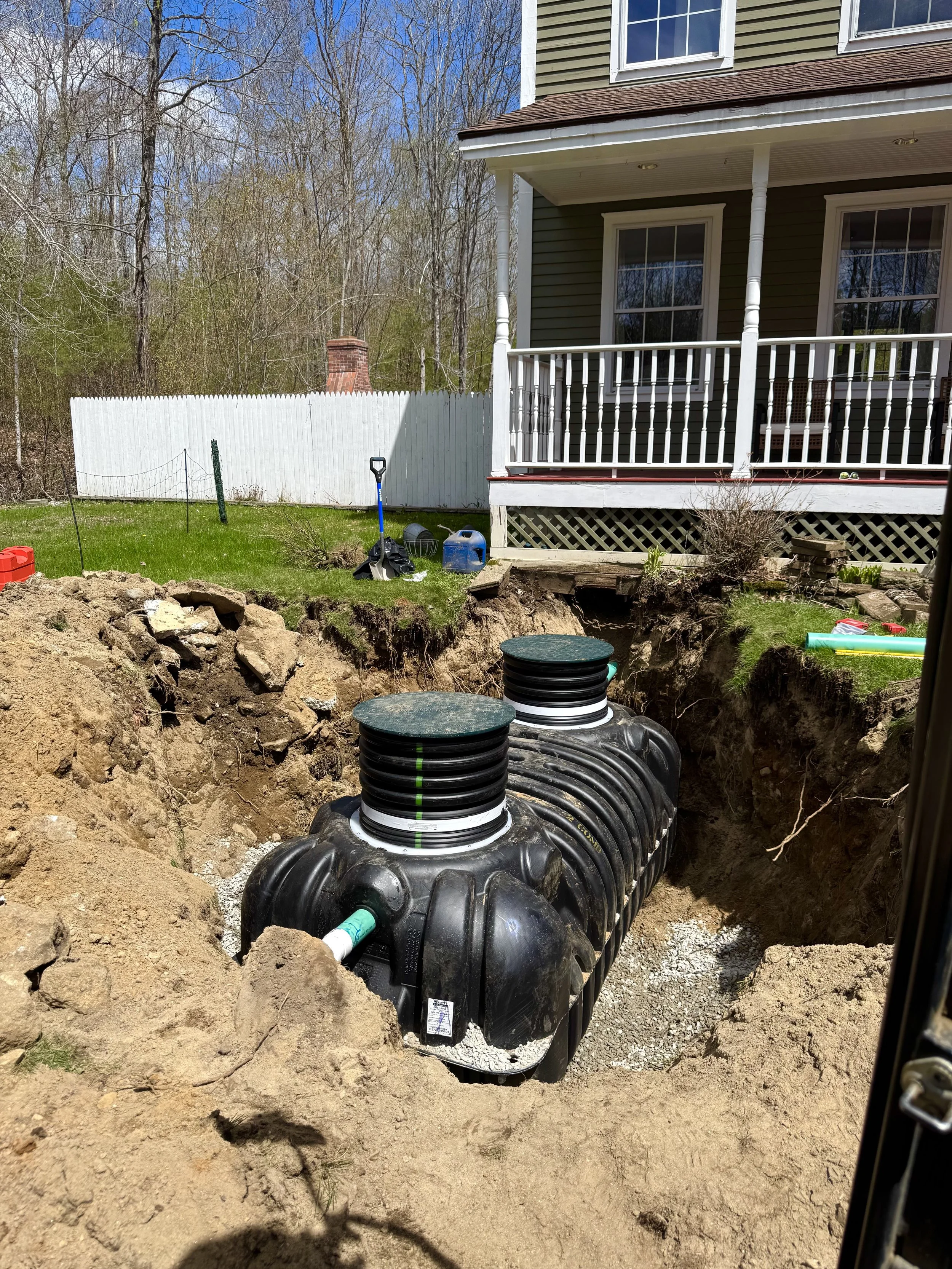 Underground plumbing installation with large black water tanks and pipe connections in a backyard.