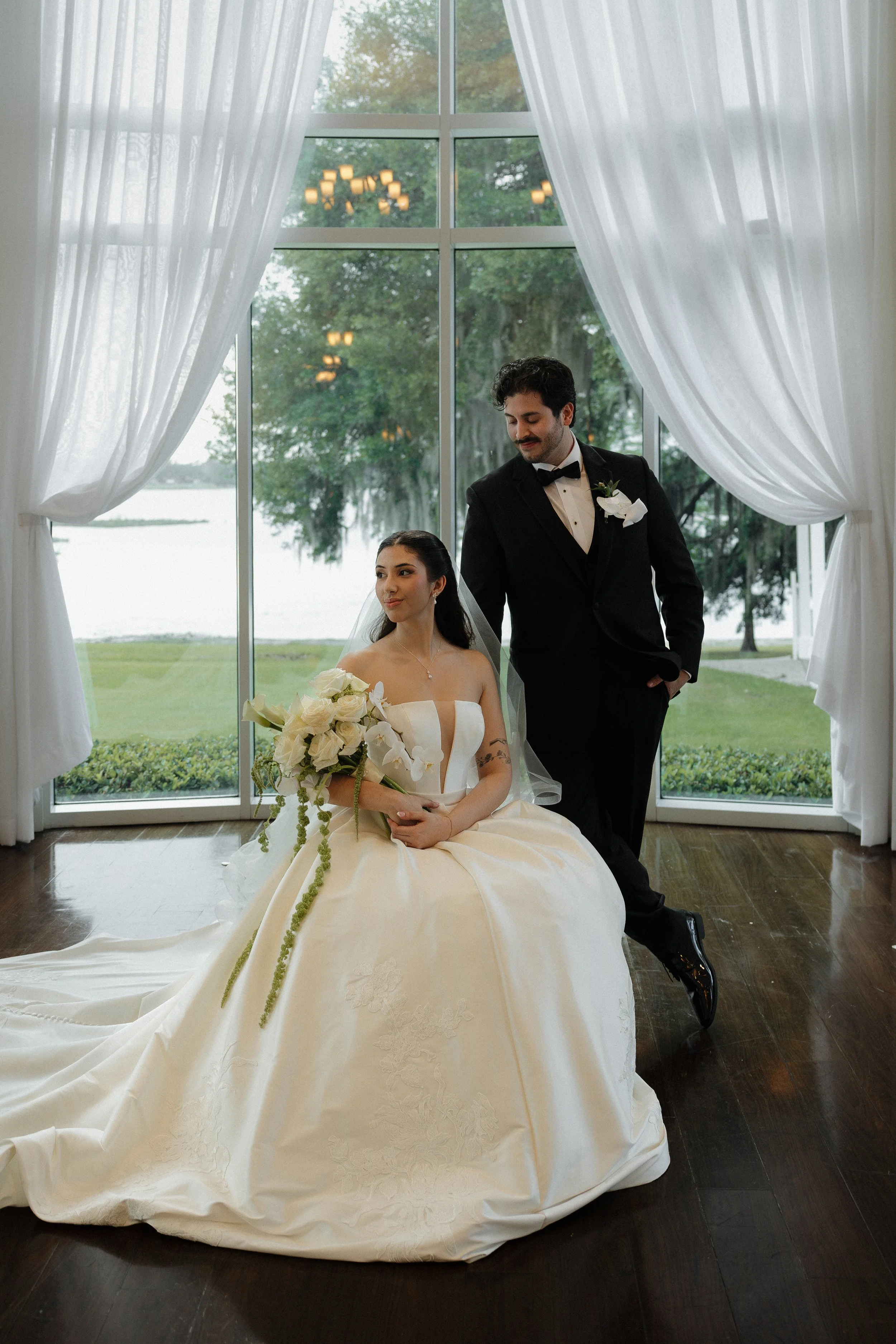 A bride and groom share a first dance at their wedding reception, with the groom dipping the bride in front of a decorated archway, illuminated by string lights and sparklers.